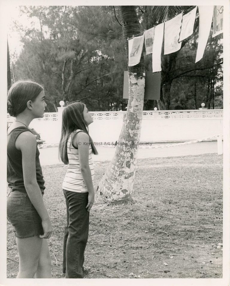 2 Unknown kids looking at art work hanging from trees