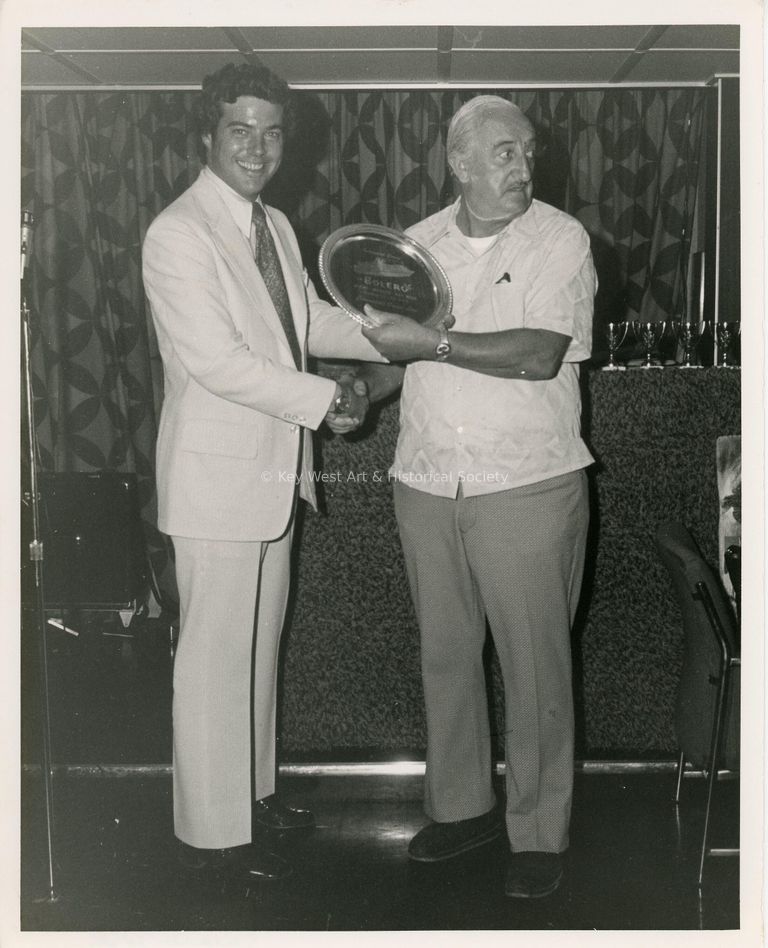 2 Unknown men standing with a plaque