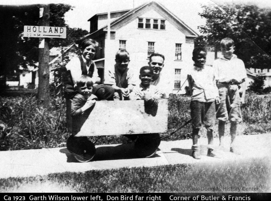 gh007.jpg 221KB; Ca 1923 Garth Wilson lower left. Don Bird far right. Corner of Butler and Francis. Six children and a man pose on the sidewalk with a box-sided wagon. The building behind them is the Judson-Heath Colonial Inn.