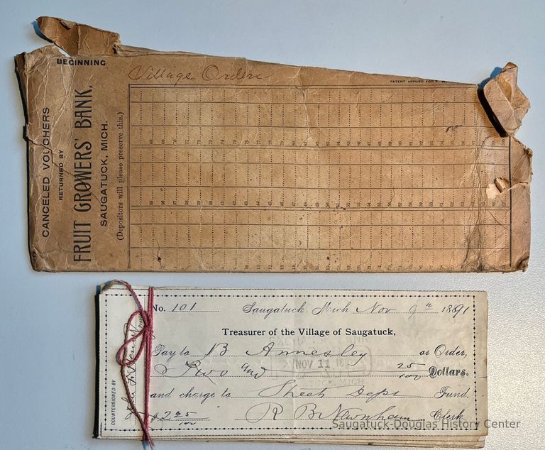          A. Fruit Growers Bank envelope
B. Sixteen checks bundled in pink twine, signed by the Saugatuck Village Treasurer R.B. Newnham in 1891.
   