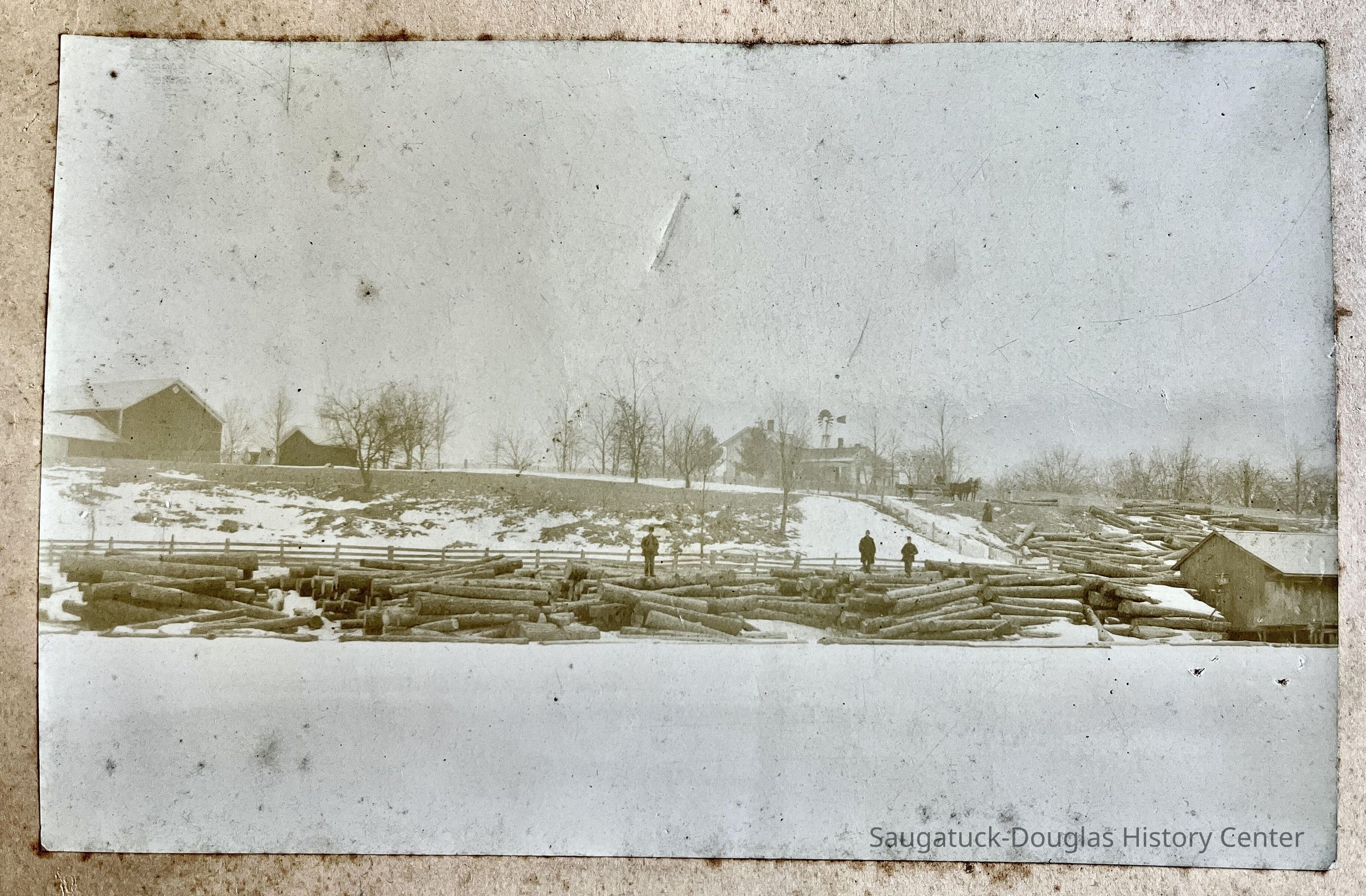 log slide: cut pine logs waiting for the spring melt-flood to carry them downriver to the lumbering mills.; May be Purdy's Riverside Farm in the distance.
