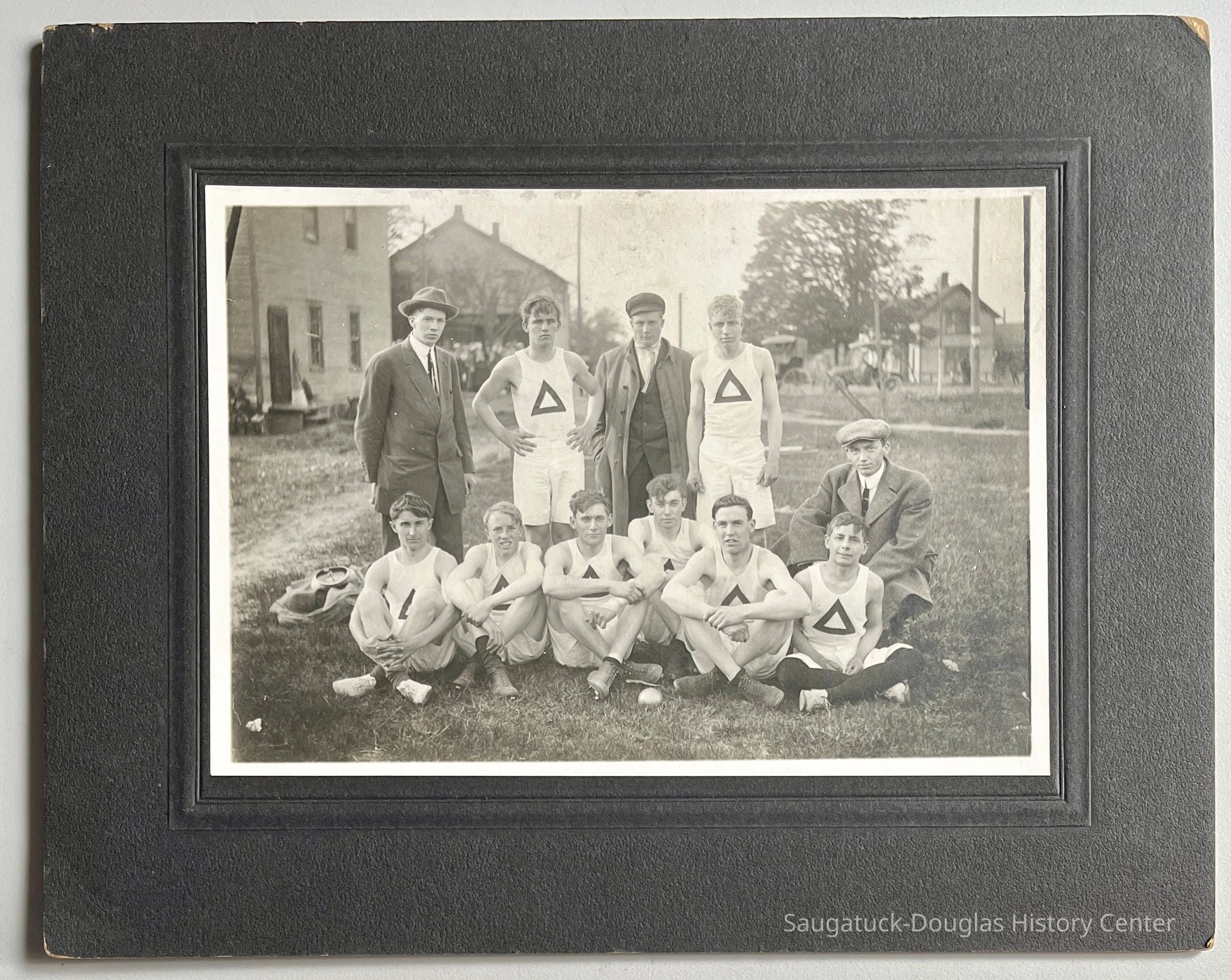 Wearing street clothing and between the two standing athletes is Dick Newnham.