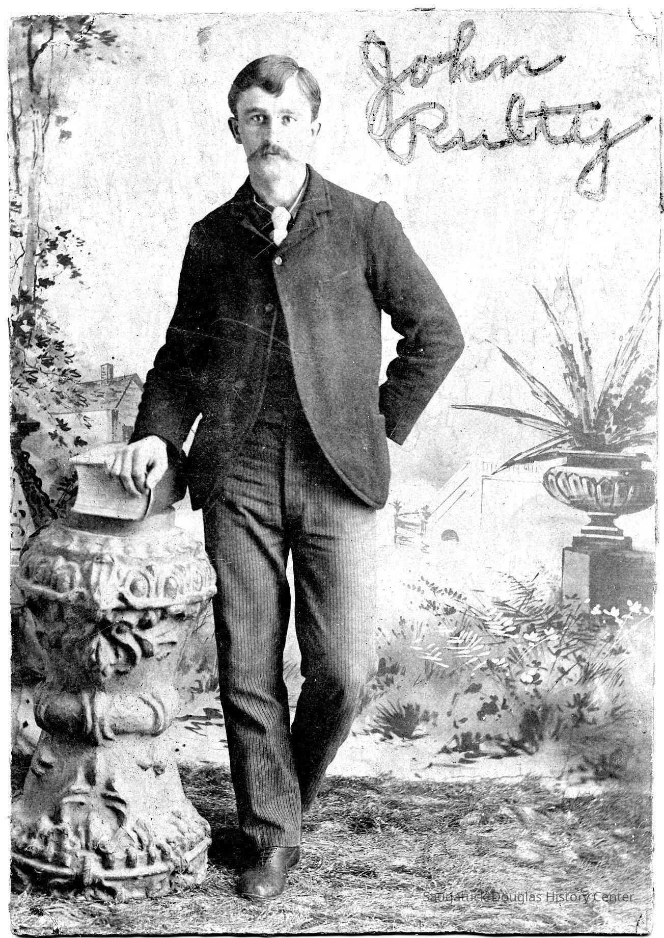          89-1-205_John_Rulty.jpg 1.1MB; John Rulty in photo studio with hand resting on thick book
   