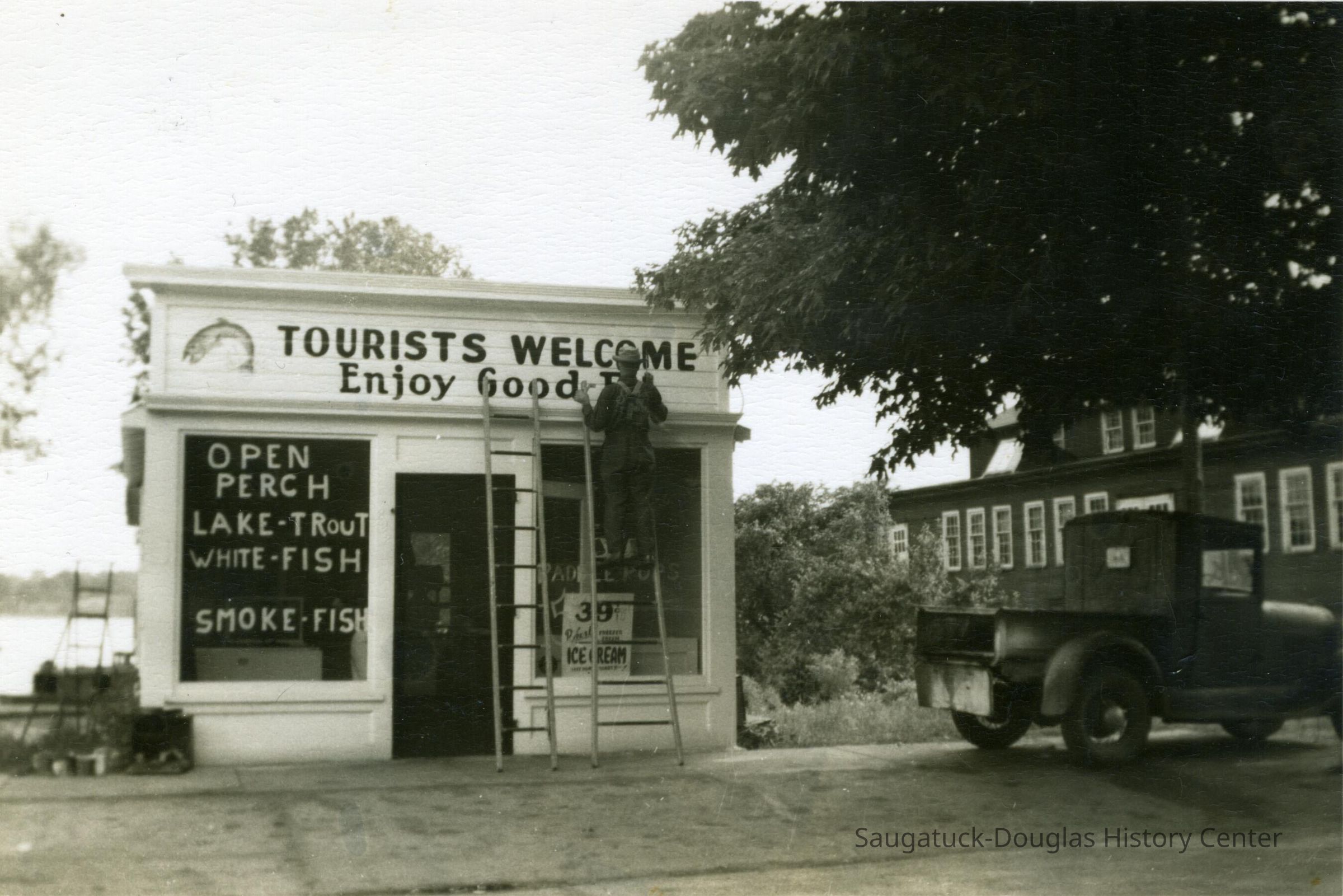Sign painter working on front facade of Diepenhorst fish market