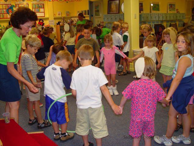 Nyla Hensley, wearing green t-shirt on the far left, leads the children in an activity