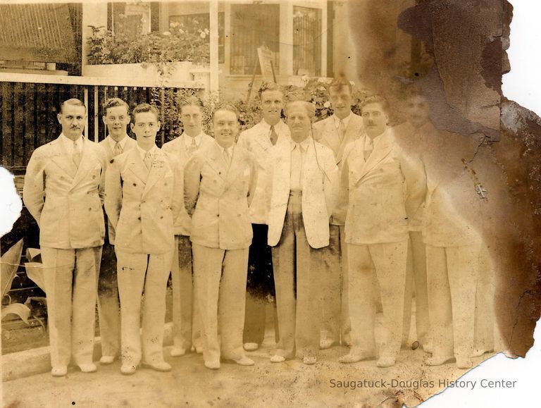          89-1-000namesOnBack.jpg 627KB; Eleven men in light-colored suits standing together for a group portrait. Many of the men have matching suits suggesting they are a  band or a wedding party. The location may be outside the Big Pavilion box office.
   