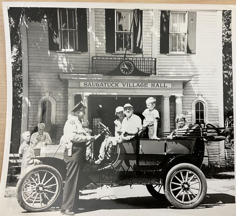          Saugatuck City Hall with Officer Henry Hungerford and car driven by Harold Whipple.; Newspaper prints of the photo identify the driver as Willard Prentice, see 2024.13.19
   