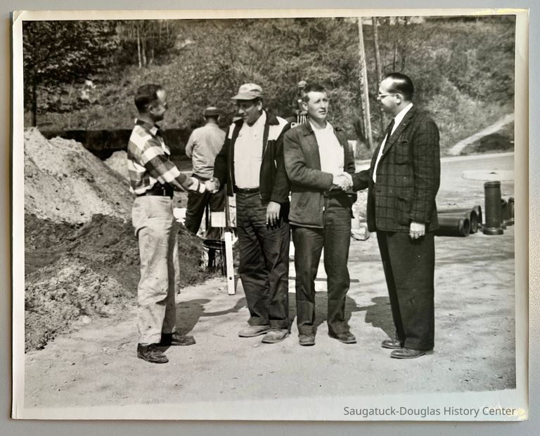          Congratulations are given to Doyle D. Barker and Raymond D. Carter of the C and D Construction company of Benton Harbor as they complete laying the sanitary sewer line in Saugatuck 40 days ahead of schedule. Left to right: Richard G. Hoffman, Saugatuck village president; Barker, Carter and Robert H. Gove of Kalamazoo, engineer. [possible original photo caption; the man in the plaid shirt is likely Richard Hoffman]
   