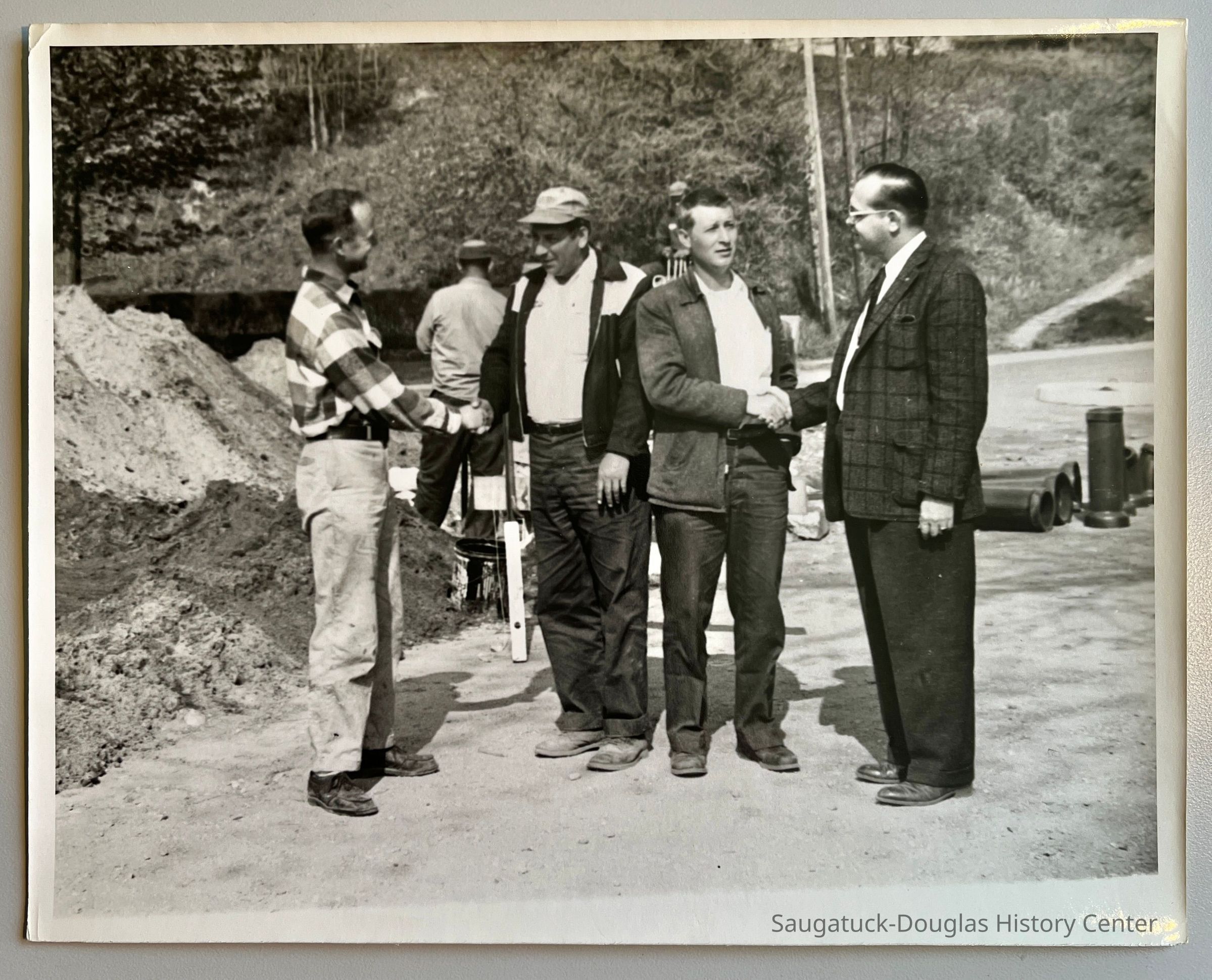          Congratulations are given to Doyle D. Barker and Raymond D. Carter of the C and D Construction company of Benton Harbor as they complete laying the sanitary sewer line in Saugatuck 40 days ahead of schedule. Left to right: Richard G. Hoffman, Saugatuck village president; Barker, Carter and Robert H. Gove of Kalamazoo, engineer. [possible original photo caption; the man in the plaid shirt is likely Richard Hoffman]
   