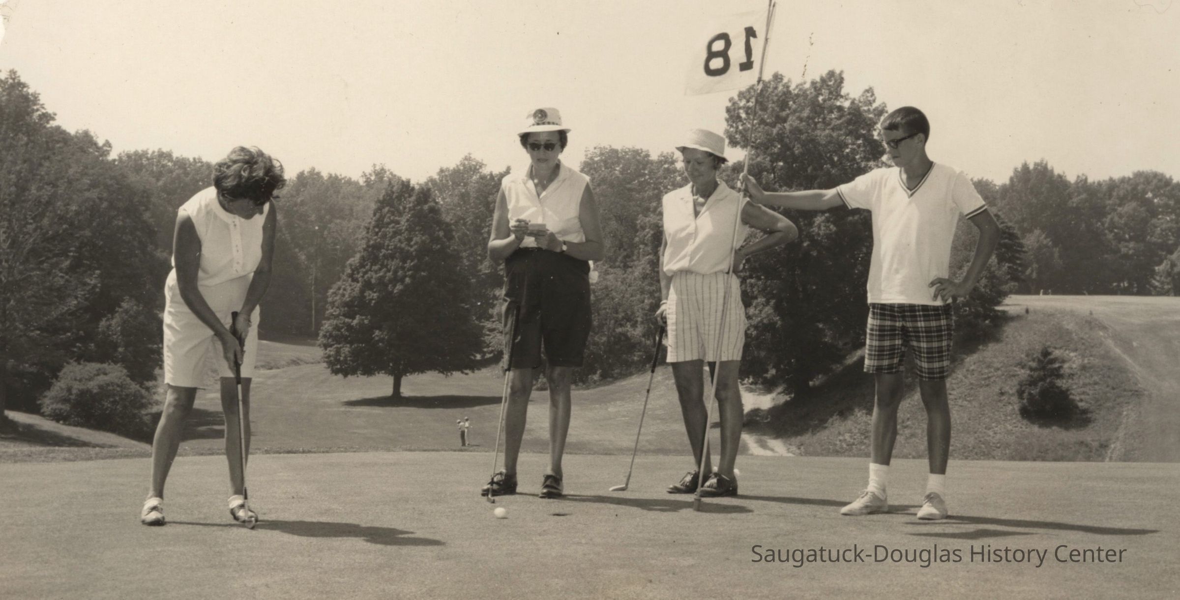 Games.Golf.Heuchan05.jpg 652KB; Westshore Golf Course St. Louis at Douglas golf joust. A woman putts while two other woman watch and a boy holds the 18th hole flag. Photo by Don Heuchan of St. Louis, MO. Date stamped Jul 23, 1965.