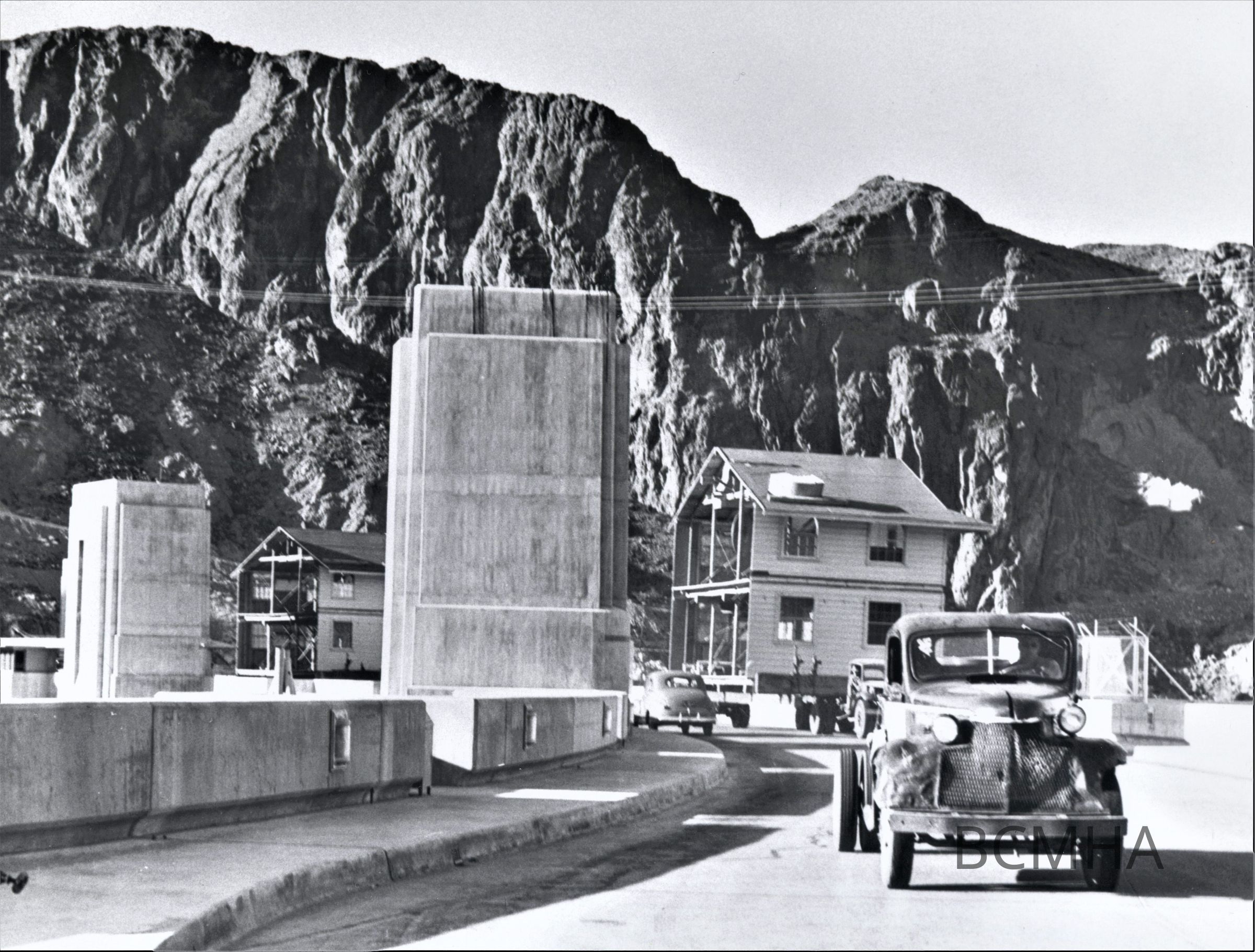 0002:2992: Housing Shortage Solution: "Shortage of housing for construction workers on the Bureau of Reclamation's Davis Dam Project on thew Colorado River has been partially solved by the purchase of ten army barrocks located at Camp Williston in Boulder City. Two 20-foot sections of one barrocks are shown crossing the rive over Boulder Dam. After the 108-mile trip to the damsite, the sections will again cross the river to be reassembled in the camp of the Utah Construction Company on the Nevada side, May 1946."