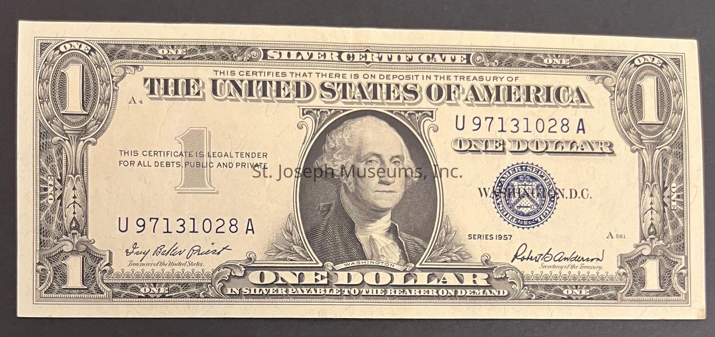 The image shows a United States one-dollar silver certificate from 1957. It features a portrait of George Washington at the center. The certificate includes the words "This certifies that there is on deposit in the Treasury of the United States of America one dollar in silver payable to the bearer on demand." Design elements include ornate borders and the denomination "1" in each corner. The blue seal and serial number “U97131028A” are prominently displayed on the right. Signatures of treasury officials are printed at the bottom. The overall design is intricate, with detailed engravings characteristic of the period.