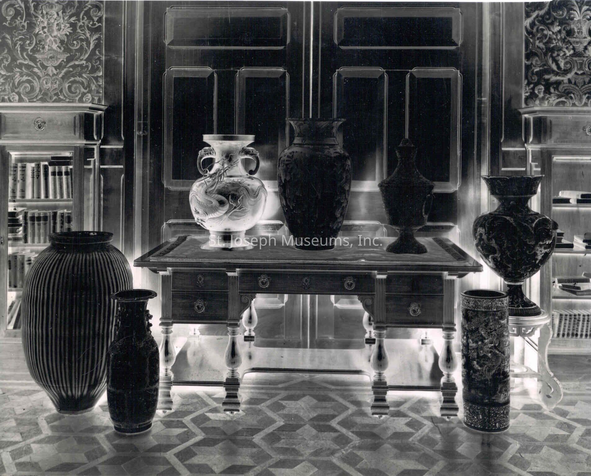 Tootle Mansion, Vase Collection, in Library, c. 1900: Copyright: 84.21.1821 Tootle Mansion, Vase Collection, in Library, c. 1900
A photo negative depicting a collection of ornately designed vases positioned both on and in front of an elegant table in the library of the Tootle Mansion in Saint Joseph, Missouri.