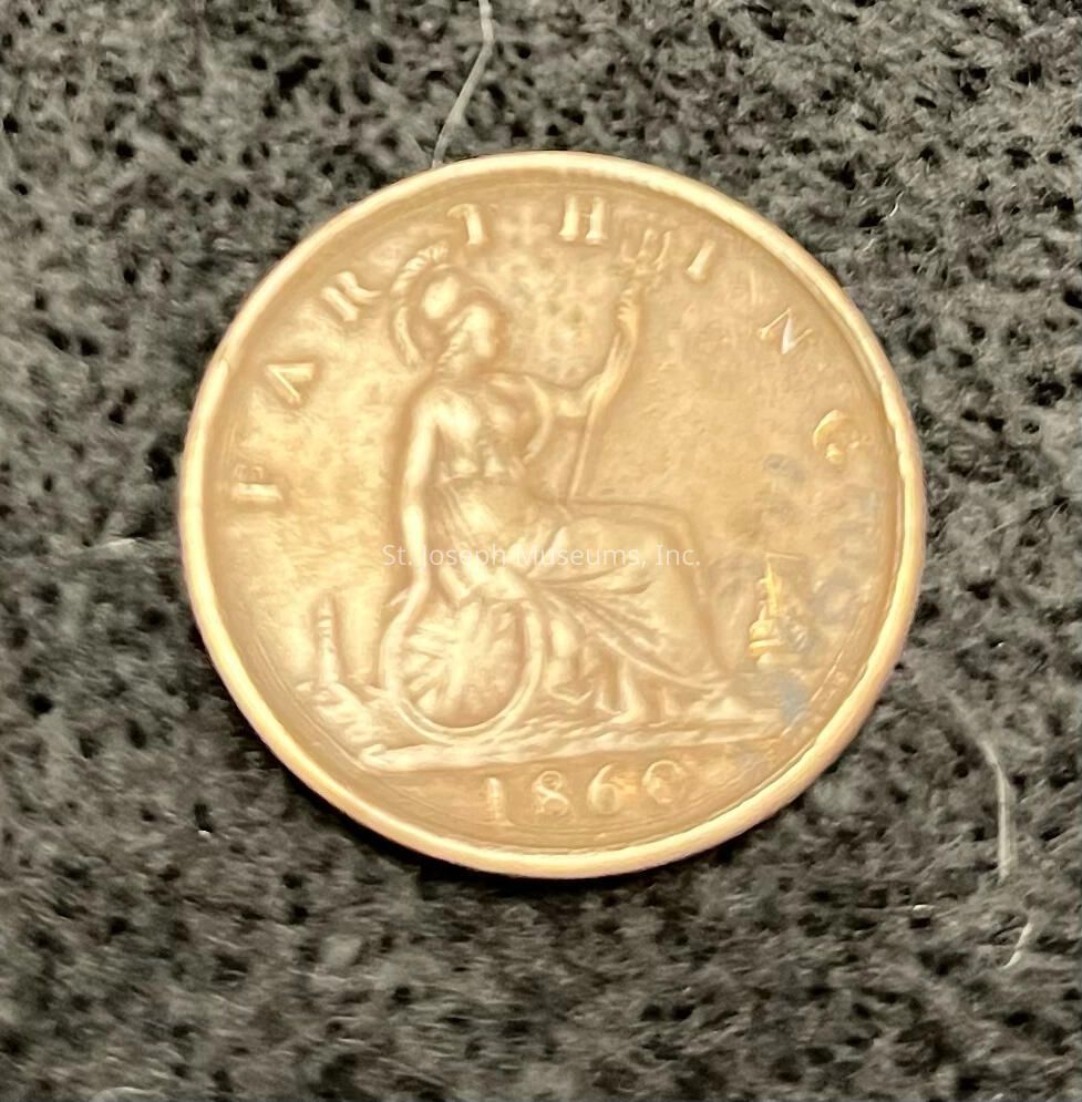 The image shows a close-up of an old coin. The coin, dated 1860, is a British farthing and features a detailed engraving of Britannia, a seated female figure wearing a helmet. She's depicted holding a trident in her left hand and has a shield by her side, reflecting a classic representation of strength and protection. The word "FARTHING" is inscribed along the top edge of the coin, clearly denoting its denomination. The coin shows signs of age with a patina that adds to its historical charm.