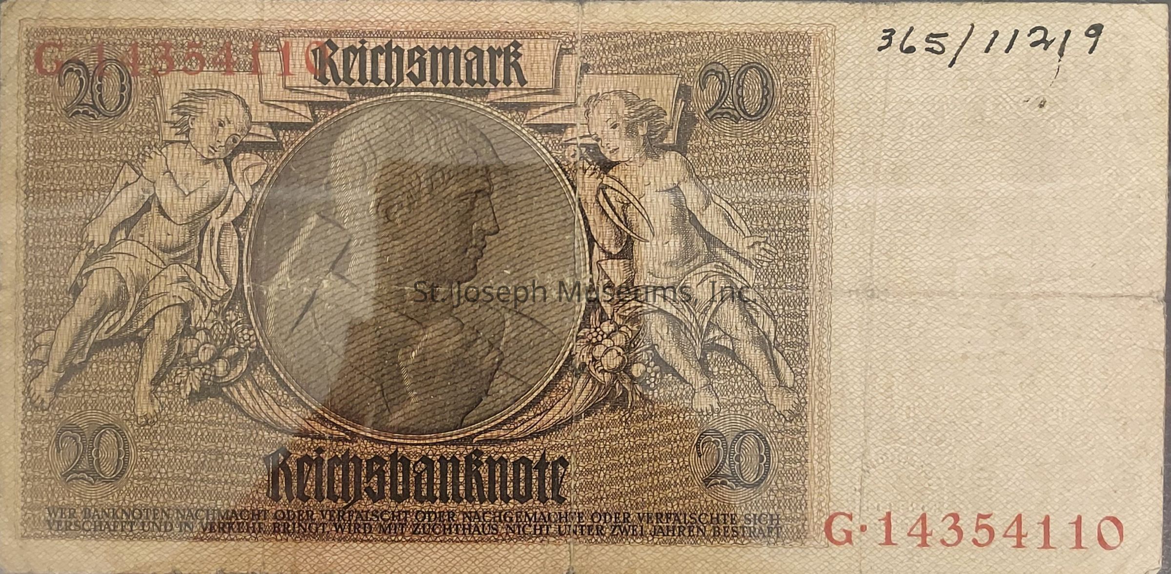 The image depicts an old 20 Reichsmark banknote, characterized by intricate designs and historical elements. The note's central feature displays a detailed circular portrait, flanked by two cherubic figures on either side. These figures are artistically illustrated, holding symbolic elements among a decorative floral motif. Above the portrait, the denomination "20" appears prominently, and the top of the note features the words "Reichsmark" in a bold, traditional script. Toward the bottom, "Reichsbanknote" is inscribed, highlighting its official status. The serial numbers are printed in red, and an additional handwritten number is present at the upper right corner. The overall design reflects a vintage aesthetic with a complex background pattern.