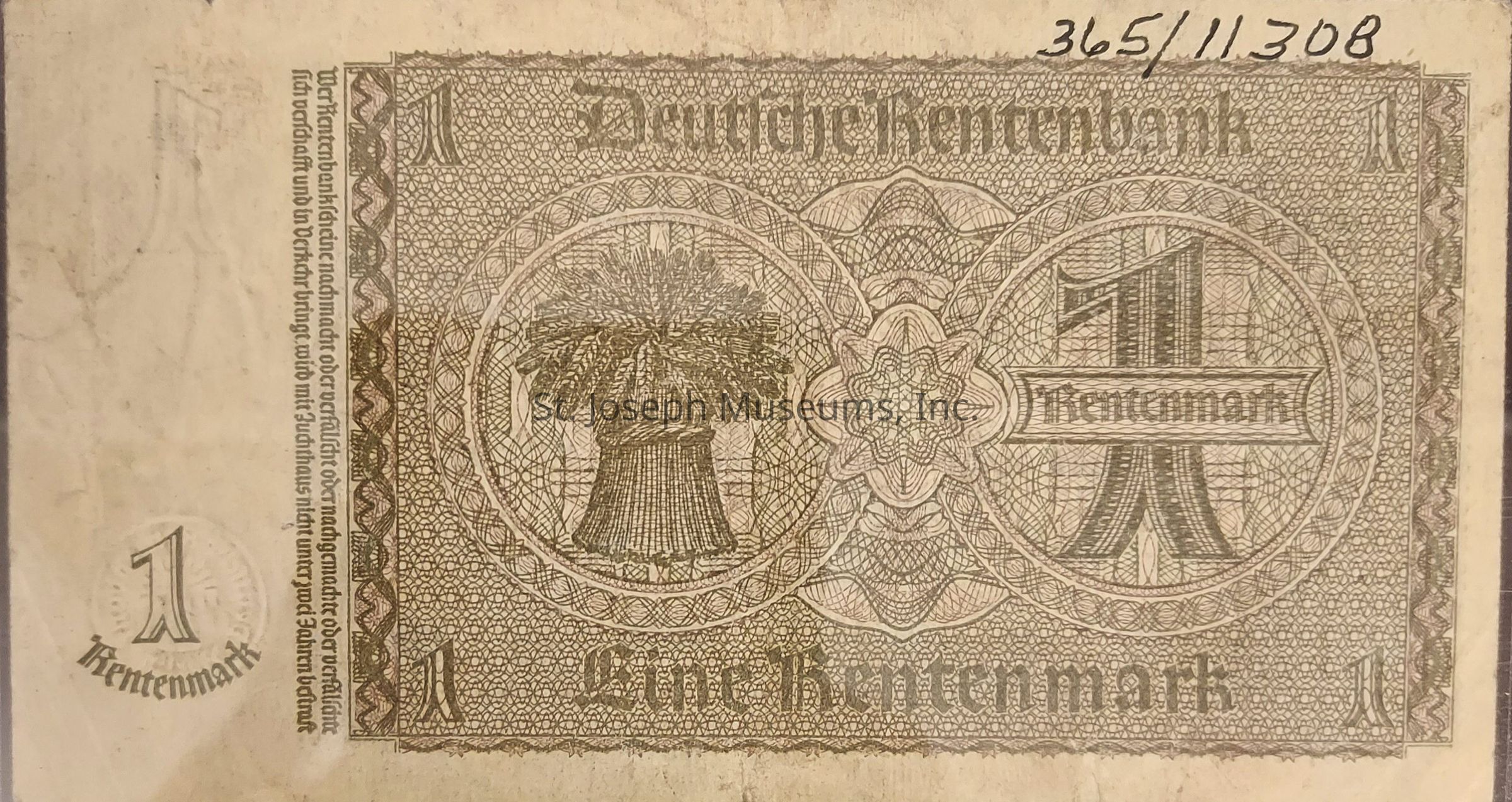 The image displays a vintage German banknote labeled as "Deutsche Rentenbank," specifically a note of "Eine Rentenmark," featuring intricate designs and patterns, including a central emblem with agricultural motifs, such as a bundle of grain. The value "1" is prominently shown at various places on the note, with ornate, symmetrical geometric patterns covering most areas. Along the left side, text appears vertically, contributing to the overall aesthetic design, and a set of handwritten numbers.