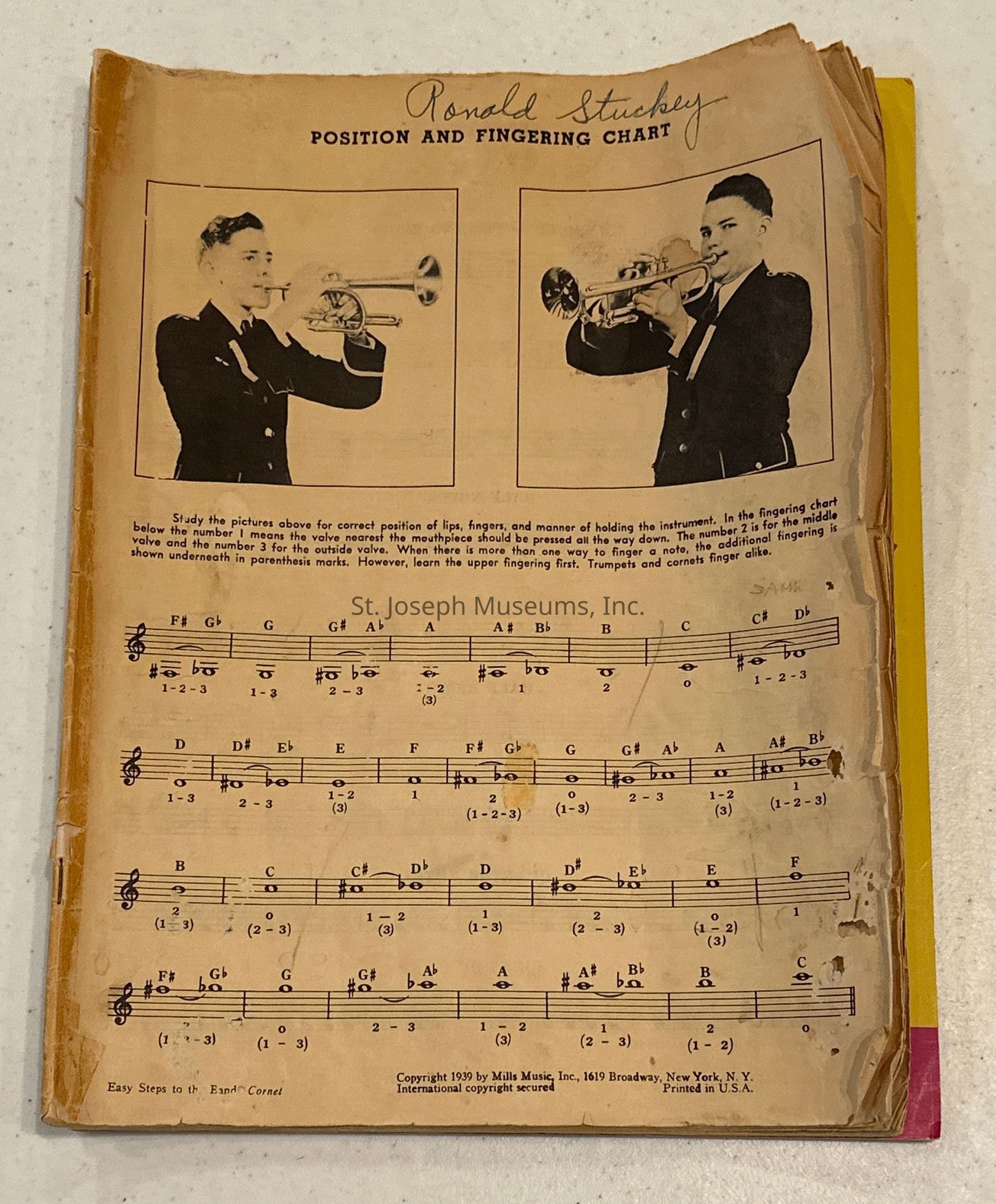 The image shows an instructional page titled "Position and Fingering Chart" by Ronald Stuckey, featuring two black and white photographs of a person demonstrating the correct trumpet positioning and embouchure. The page is yellowed and slightly tattered, indicating its age and use. Below the images, text provides detailed instructions on finger positions for playing various notes on the trumpet or cornet, using numbers to indicate which valves to press. The musical notes and corresponding fingering positions span several lines of sheet music, covering notes from F# to F across various octaves. The copyright at the bottom indicates the page was published in 1939 by Mills Music Inc., located in New York.