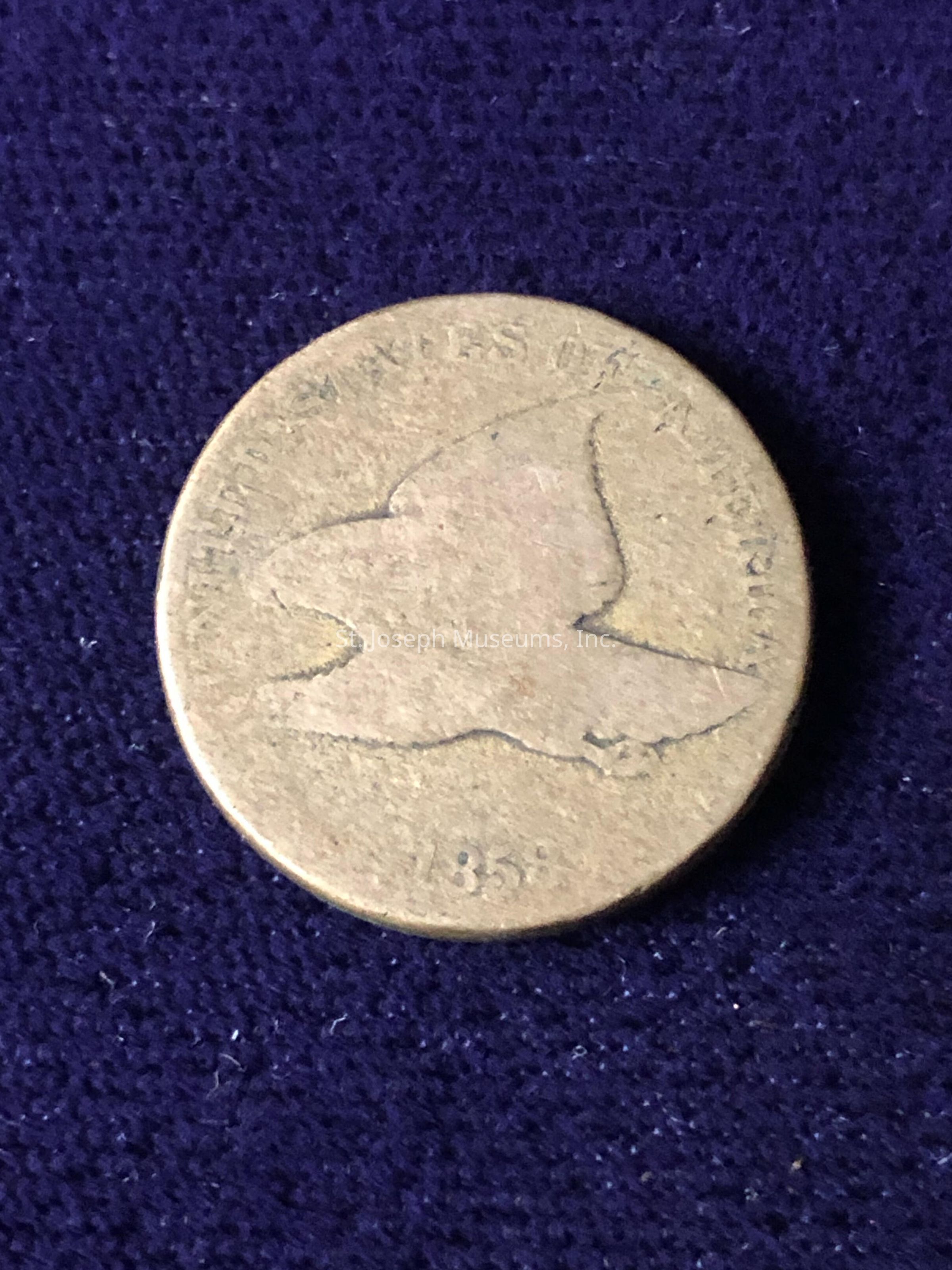 The coin appears weathered, suggesting age, and it has the year "1858" inscribed at the bottom, indicating its historical significance. The edges of the coin are slightly worn, consistent with frequent use over time, and the bird design is prominent, capturing a moment of dynamic motion. The texture of the coin surface reflects its antiquity, and despite the visible wear, the details remain distinct enough to convey its original craftsmanship. The overall composition of the image highlights the coin's unique features, presenting a sense of nostalgia and historical intrigue, while the dark blue background provides a stark contrast, allowing the golden hue of the coin to stand out prominently in the photograph.