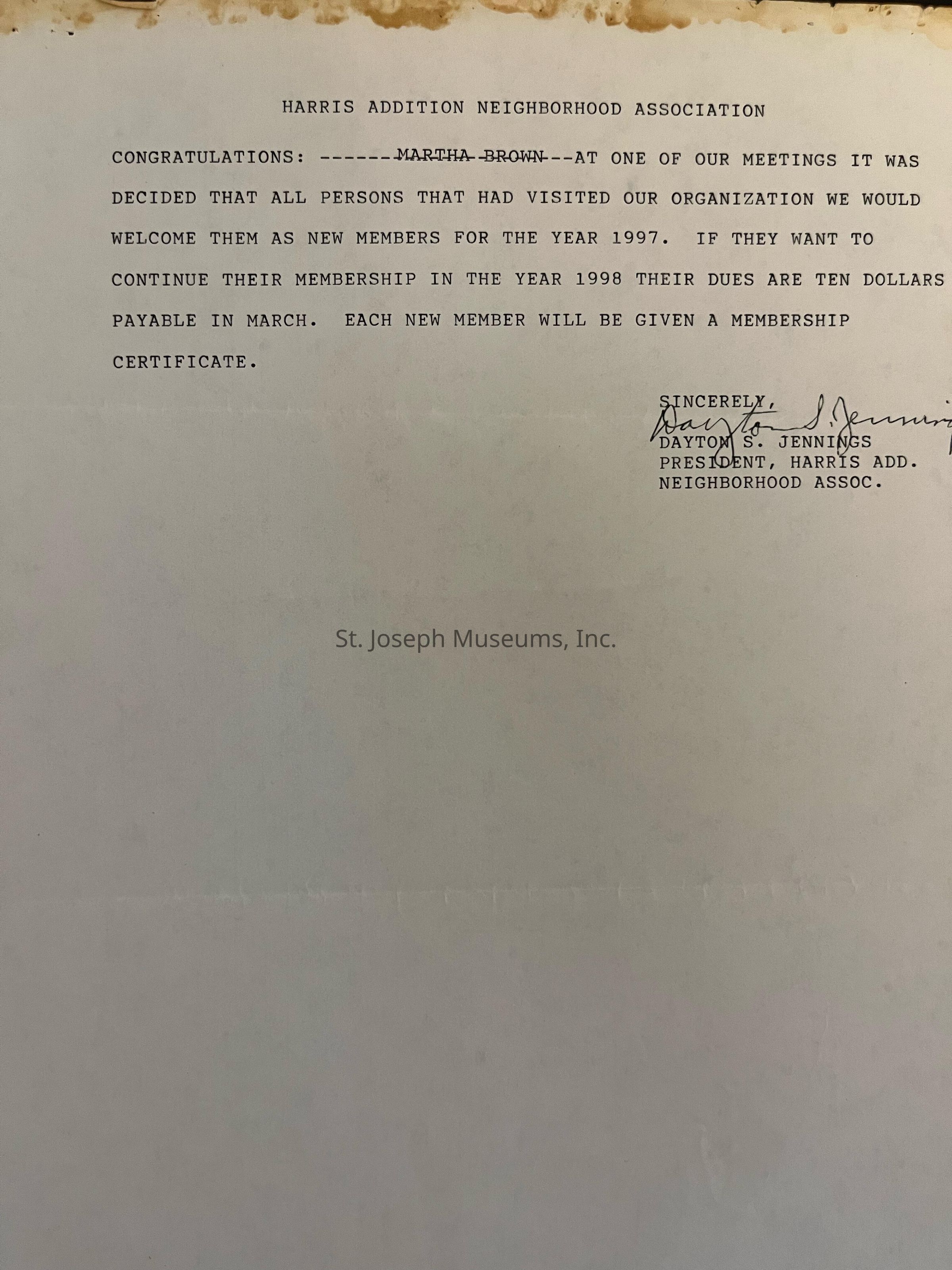 The image shows a letter from the Harris Addition Neighborhood Association congratulating a new member for joining in 1997. The letter states that at a meeting, the decision was made to welcome all visiting individuals as new members for the year. It also mentions that if new members wish to continue their membership in 1998, they need to pay a due of ten dollars in March. Additionally, every new member will receive a membership certificate. The letter is signed by Dayton S. Jennings, the President of the Harris Addition Neighborhood Association. The page shows some signs of aging, with a brown stain at the top.