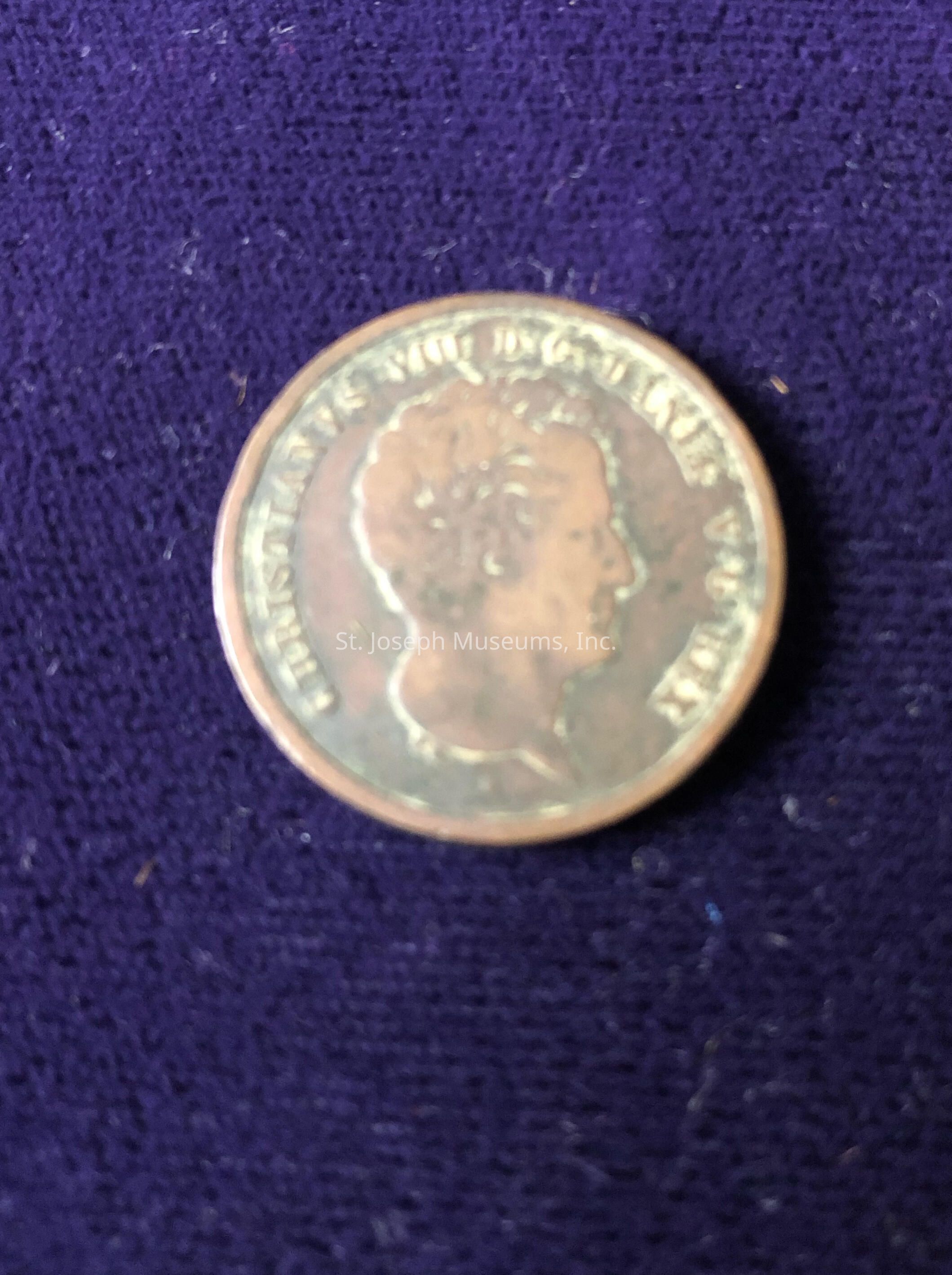 Featuring an embossed profile of a person's head facing right, with inscriptions surrounding the edge, highlighting intricate details on the coin that suggest historical or cultural significance, as the craftsmanship showcases a blend of artistry and precision often seen in older currencies, making it a fascinating object for collectors or historians interested in numismatics; despite the blurriness affecting the clarity of the inscriptions, the coin's weathered appearance hints at its age and past utility in economic transactions, potentially serving as a link to the era in which it circulated, thereby capturing the imagination of those intrigued by the stories coins can tell about the societies that minted and used them, forming an essential connection between art, history, and economy, while the fabric backdrop enhances the visual contrast, spotlighting the coin's metallic sheen against a soft textile depth that could signify careful curation or collection display, inviting viewers to ponder the journey of the coin through time.