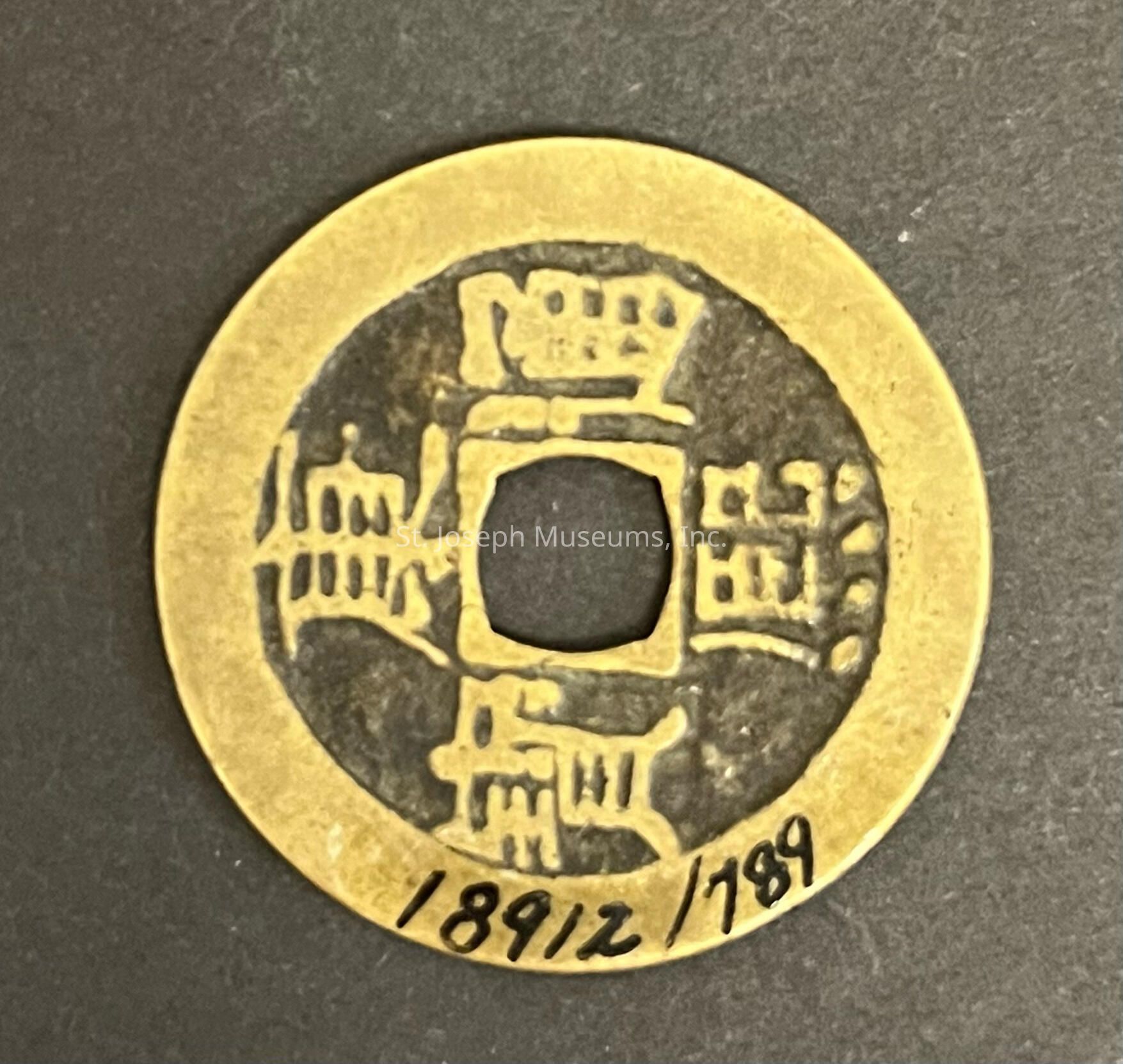 This image features a traditional round coin with a square hole at its center, which is characteristic of old Chinese currency. The surface of the coin is inscribed with Chinese characters, suggesting its historical and cultural significance. The coin's outer rim is smooth, and it appears to be made of metal with a golden hue. The numbers "1891/789" are written on the bottom edge in black ink, possibly indicating a catalog number or a reference for identification. The coin is set against a plain dark background, highlighting its details and giving it an antique appearance. The intricate design of the characters and the distinct central hole contribute to the coin's unique and authentic aesthetic, reflecting a bygone era.