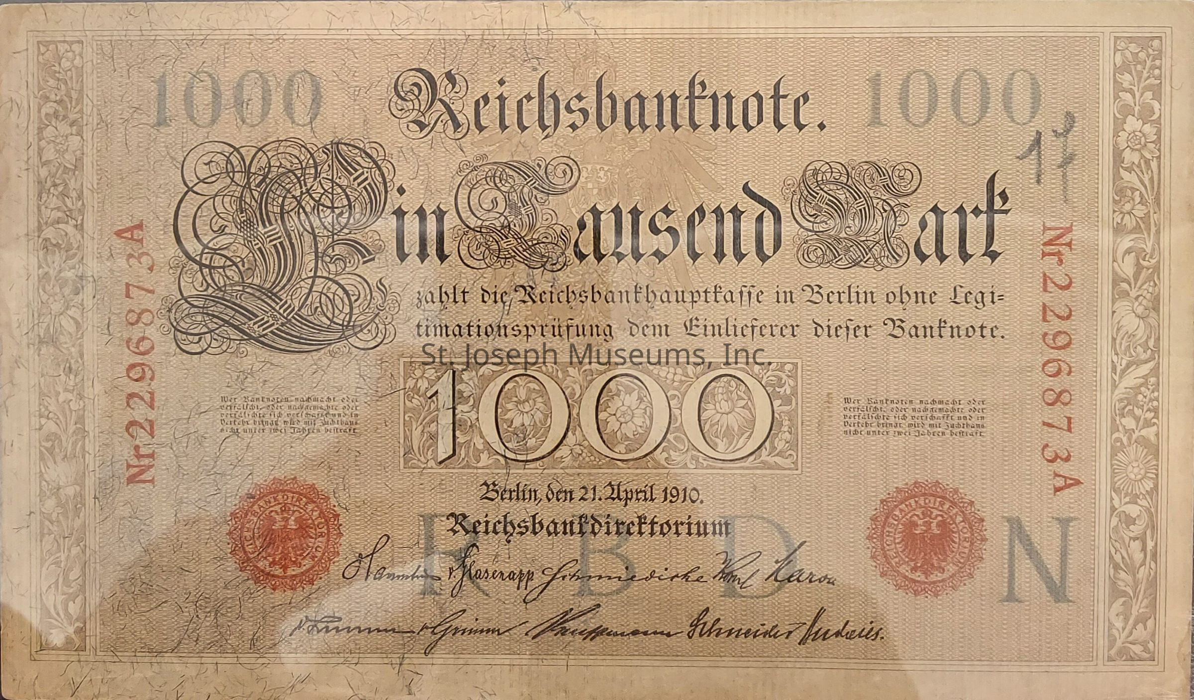 The image depicts a historical banknote from the Reichsbanknote series, denominated as a "Tausend Mark" or "One Thousand Marks," issued in Germany, specifically designed with intricate and ornate detailing, including elegant calligraphy and floral motifs along the borders. The note prominently displays the denomination "1000" in stylized numerals, surrounded by decorative floral patterns, with the text printed in an elaborate, old-style Gothic font. A red seal with an eagle emblem is visible on the note, signifying official validation, along with several signatures at the bottom, likely authorized personnel from the bank. The text on the note mentions the issuance by the central bank in Berlin, dated April 21, 1910, offering payment to the bearer without the need for identity verification. The serial number is printed in red on the left and right sides, providing uniqueness to this particular bill. The overall color scheme predominantly features warm beige tones, with intricate linework and textured background, reflecting the design