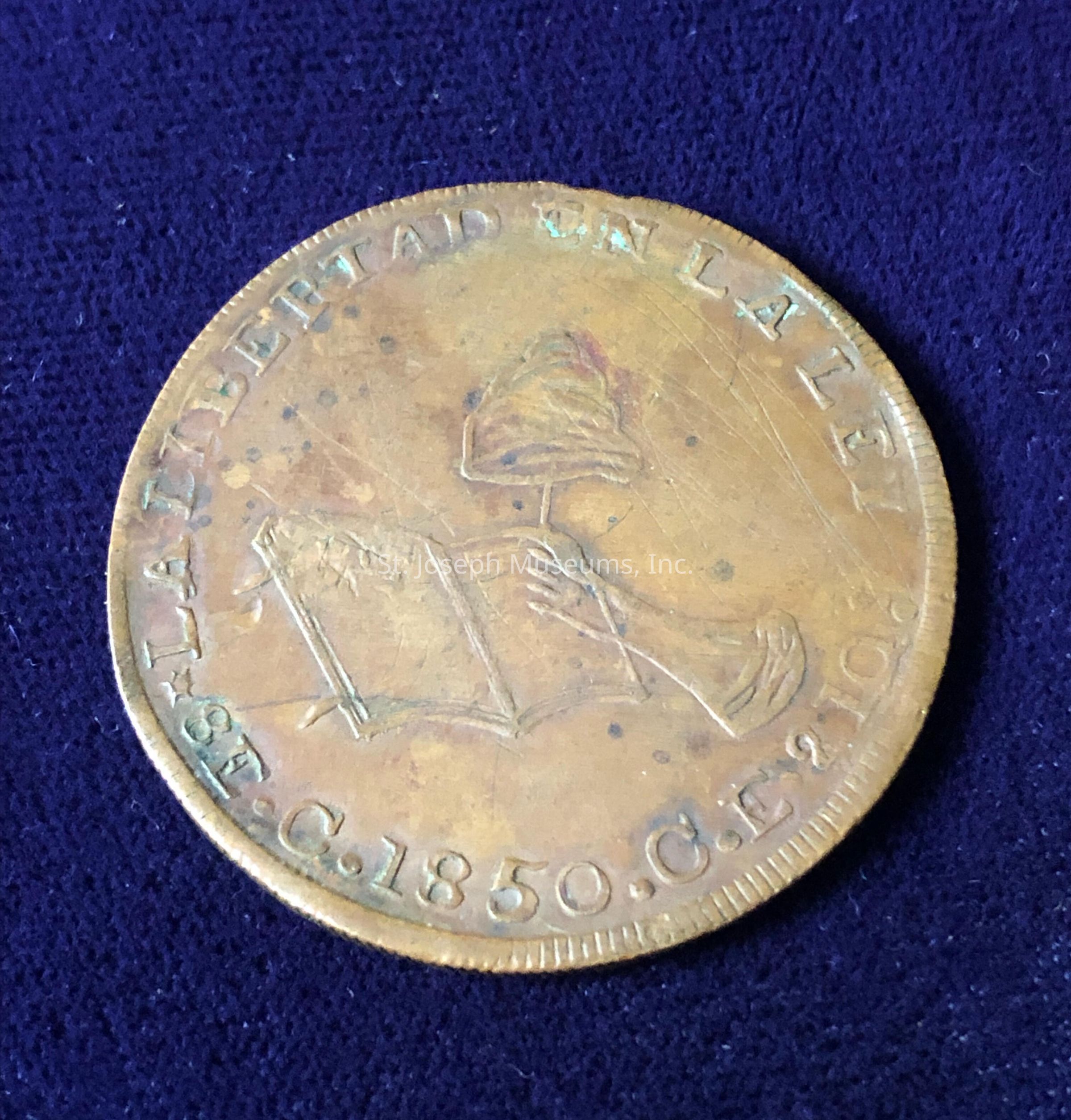The coin features a slightly tarnished copper hue, suggestive of its age, and is embossed with the words "LIBERTAD" and "UN LA LEY" along its perimeter. At its center, a detailed design depicts a hand holding a cap atop a staff, possibly a symbol linked to liberty or freedom. The lower part of the coin bears the inscription "C.1850.G.F.210," hinting at its minting year and potentially the region or mint mark. The coin's edge is decorated with fine ridges, adding to its intricate craftsmanship and historical allure.