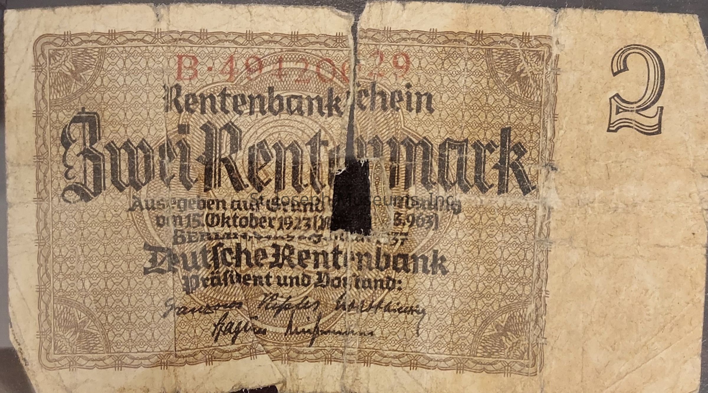 The image shows an old, worn German banknote, specifically a "Zwei Rentenmark" from the Rentenbank, indicating a value of 2 rentenmarks. The note features intricate patterns and German text in a blackletter typeface, with a noticeable series of folds, creases, and a significant tear running down the middle. The serial number "B 19176129" is printed in red at the top, and there are signatures at the bottom of the note. The watermark patterns and age-related wear and tear give the note an antique appearance, reflecting its historical context from the post-World War I era of economic stabilization in Germany.