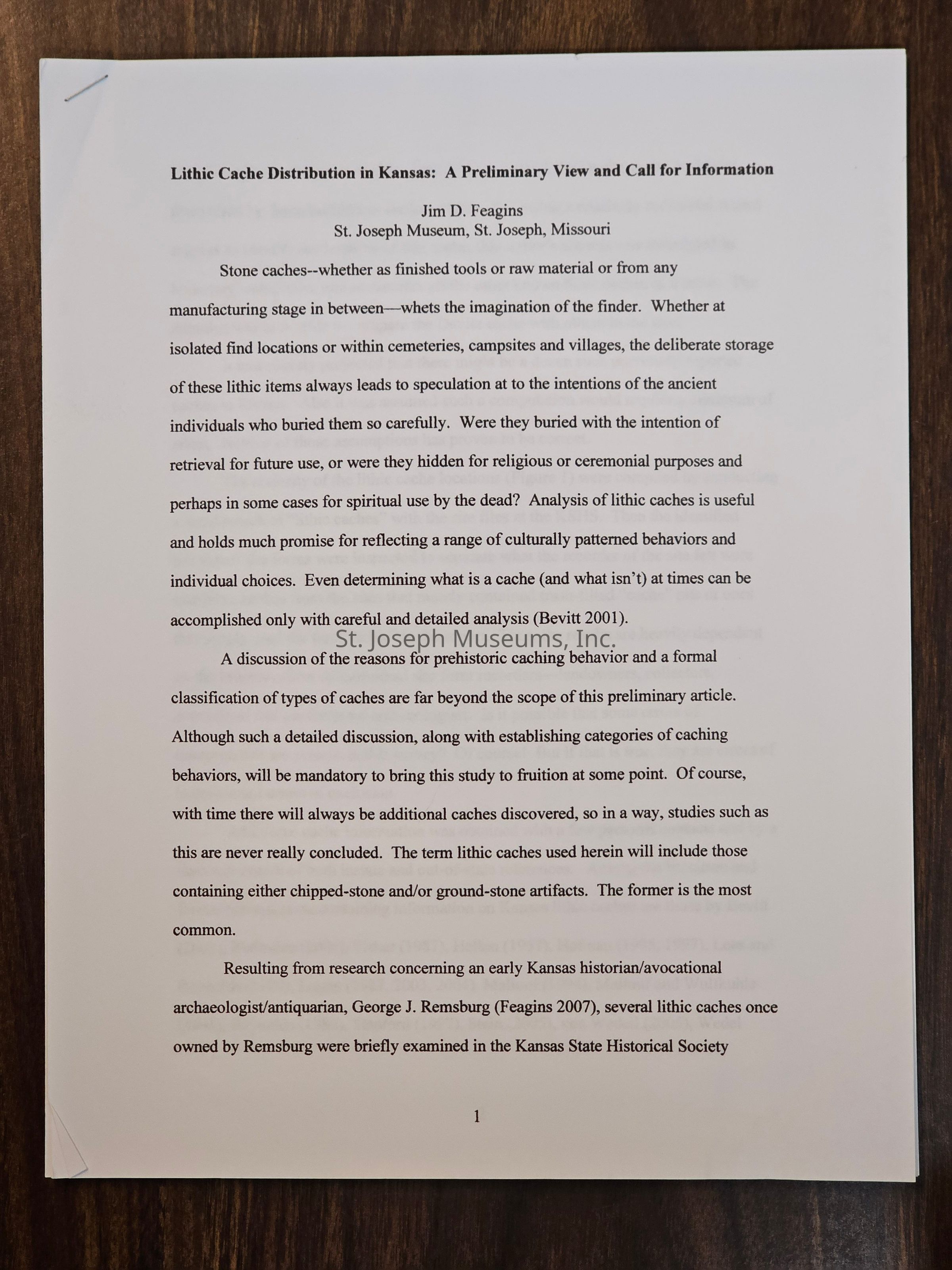 The image shows a page from a document titled "Lithic Cache Distribution in Kansas: A Preliminary View and Call for Information" by Jim D. Feagins from the St. Joseph Museum in Missouri. The text discusses the significance of stone caches, addressing their role as either finished tools or raw material, and ponders the intentions behind their deliberate storage by ancient individuals. The document highlights the potential uses of stone caches for religious, ceremonial, or spiritual purposes