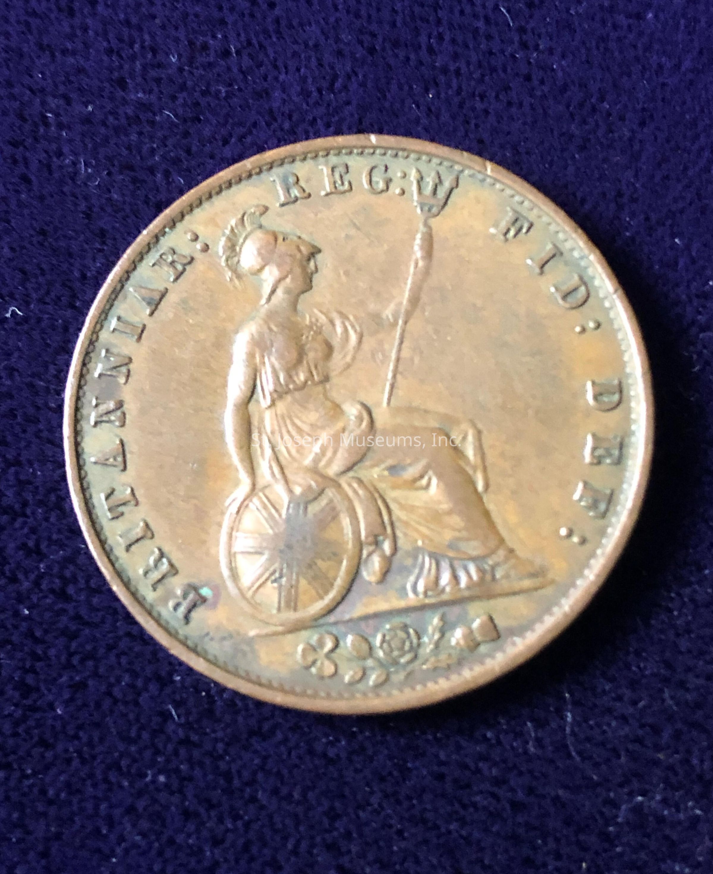 The coin features an engraving of a seated figure holding a trident, a depiction representative of Britannia. Surrounding the figure, inscriptions in capital letters read “BRITANNIAR: REG: FID: DEF:,” a Latin phrase often used on historical British currency, which stands for "Queen of the Britains, Defender of the Faith." The figure is adorned with a helmet and sits beside a shield embellished with emblems, including a cross. Below the figure is a decorative arrangement with a floral motif and the year “1894” inscribed, indicating the coin's minting year. The coin has a slightly worn appearance, suggesting its age and historical value. The overall hue of the coin is a warm, tarnished bronze, indicative of its material and era. The intricate details and engravings reflect the craftsmanship and artistry of the period during which it was produced, giving a glimpse into the aesthetic and cultural significance of