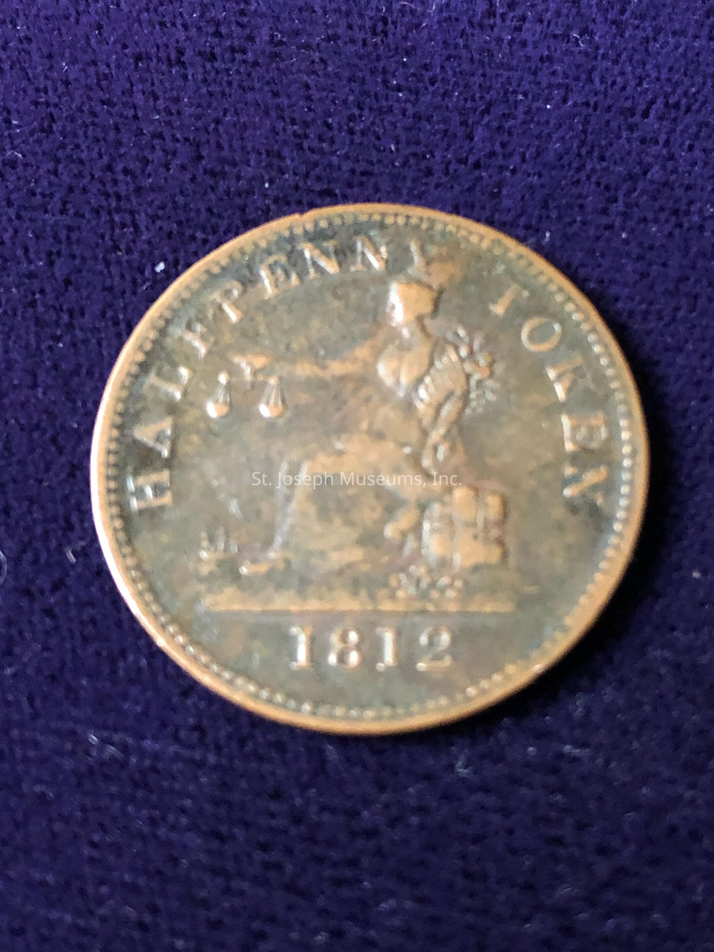 The image depicts an antique halfpenny token from 1812. The coin has an intricate design featuring a seated figure holding a pair of scales, symbolizing justice or trade. The words "HALFPENNY TOKEN" adorn the top edge of the coin, while the date "1812" is prominently displayed at the bottom. The coin's surface shows signs of age, with a patina that gives it a vintage appearance. This token likely served as a substitute currency during a time when there was a shortage of official coinage, making it a fascinating piece of numismatic history. The coin's bronze tones, highlighting its detailed engraving and craftsmanship. In the past, such tokens were often issued by private businesses or local authorities to facilitate trade and commerce in the absence of governmental minting. This coin is a testament to the creative solutions societies have employed to overcome economic challenges. The coin's historical significance is enhanced by its preserved state, allowing
