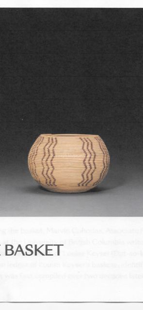 The image features a spherical basket with an intricate design, characterized by horizontal lines creating a subtle texture across its surface. Vertical patterns, composed of wavy black lines, add a decorative touch, enhancing the basket’s aesthetic appeal. The basket's natural, light-toned material gives it an organic feel, suggesting it is crafted from traditional materials such as reeds or grasses. It is placed centrally, with a soft shadow beneath it, set against a minimalist, dark gray background that enhances the basket's features by providing a strong contrast. The simplicity and elegance of the design reflect a balance of artistry and functionality, highlighting craftsmanship and attention to detail. The surrounding space is minimal, emphasizing the basket as the focal point of the image, inviting appreciation for its traditional and possibly cultural significance. The bottom edge of the image includes blurred text, which does not detract from the visual prominence of the basket itself, maintaining a clean and focused composition throughout the visual presentation.