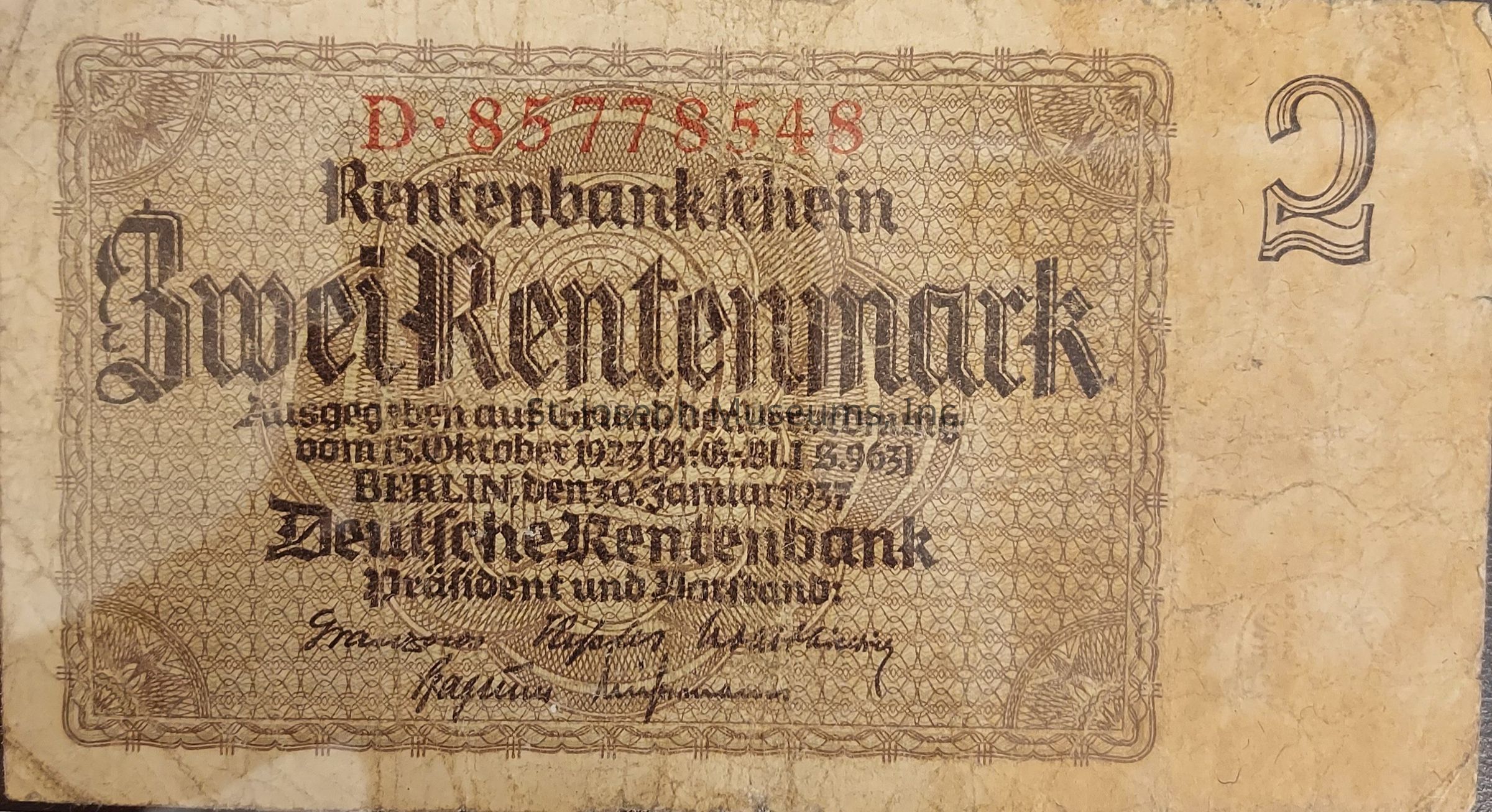 The image shows an old German banknote with "Zwei Rentenmark" prominently printed in large, decorative Gothic-style script across the center. Above the denomination are intricate patterns forming an elaborate border around the edges. The serial number "D-85778548" is printed in red ink at the top. Below the central text, there is detailed information in smaller print, including dates and a mention of Berlin. The banknote displays two signatures at the bottom, indicating the president and another authority's approval. The number "2" is clearly visible in the top right corner. The background features a complex lattice of geometric patterns, and the parchment appears aged and worn.