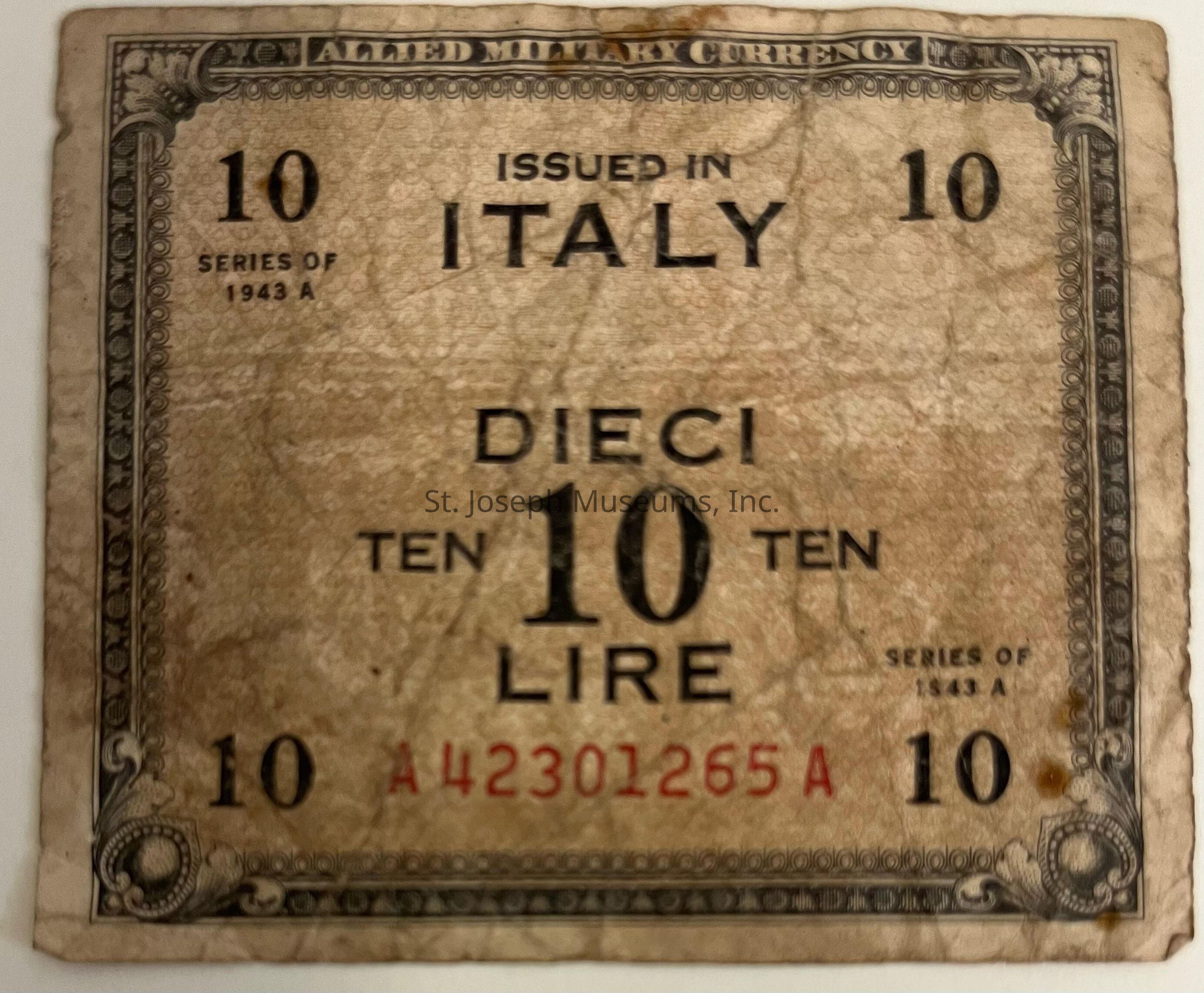 The image depicts an old, worn Allied Military Currency note from Italy, valued at ten lire, issued in 1943. The note features ornate designs around the edges, with the words "Issued in Italy" prominently in the center. The denomination is indicated in both Italian (dieci) and English (ten) flanking a large numeral "10" in the center. The serial number "A42301265A" is printed in red at the bottom, and the corners of the note bear decorative elements, providing an antique appearance. The series of the currency is noted as "1943 A," indicating its historical context during World War II.