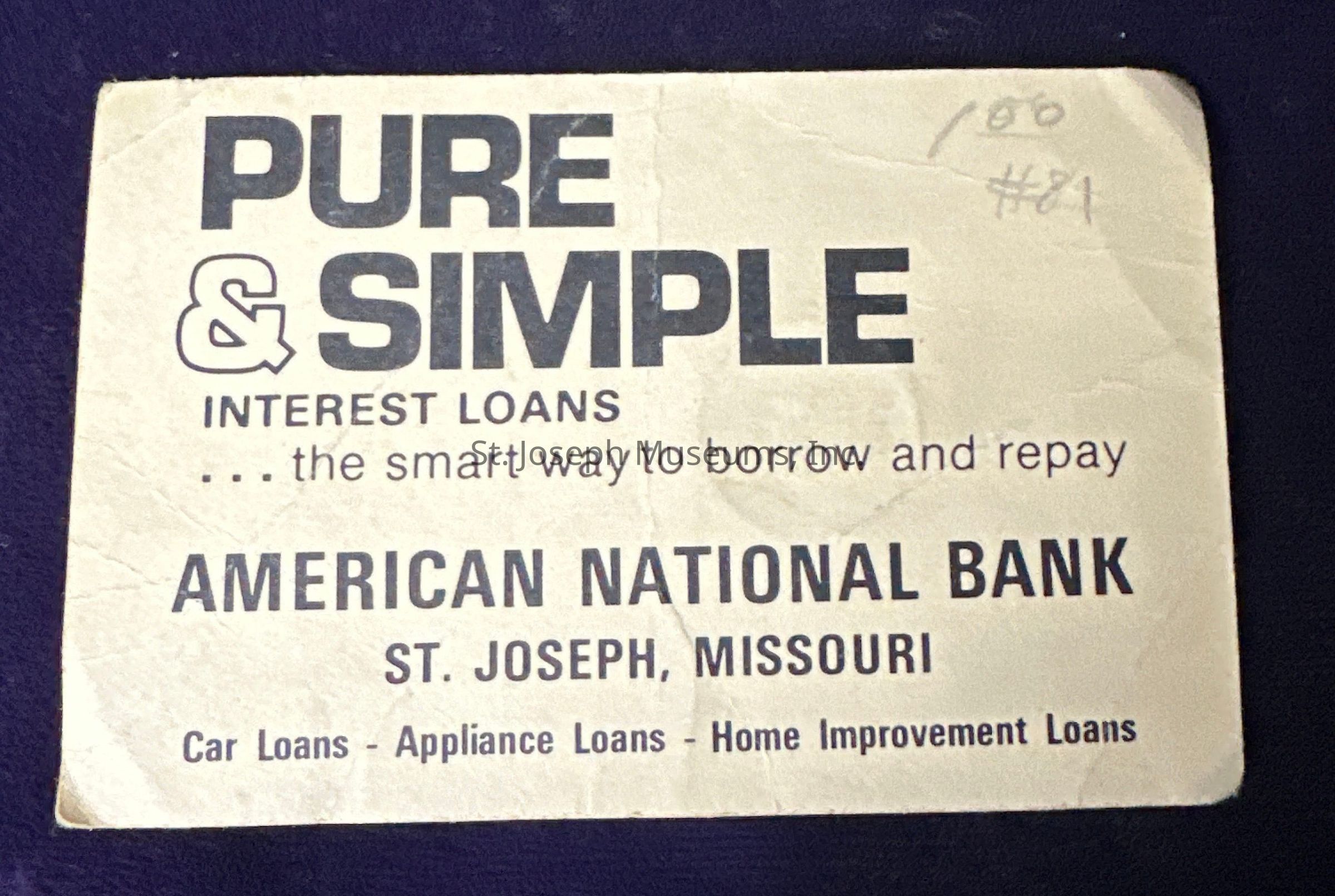 The image is a vintage advertisement from American National Bank located in St. Joseph, Missouri, promoting "Pure & Simple" interest loans with the tagline, "the smart way to borrow and repay." The advertisement emphasizes the availability of car loans, appliance loans, and home improvement loans. The design is straightforward, featuring bold, black typography on a plain background, and some handwritten marks, “100” and “#81,” can be seen on the top right corner, suggesting it has been cataloged or referenced for a specific purpose.