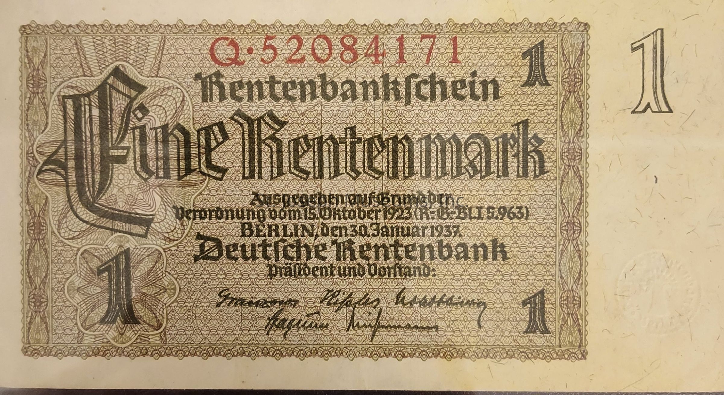 The image shows an old German banknote known as a "Rentenmark," specifically a one Rentenmark bill. It features intricate patterns and an ornate design, indicative of early 20th century German currency. Prominently displayed on the left side is the stylized word “Eine” meaning “one,” with the word "Rentenmark" in a bold blackletter font. The serial number, Q-52084171, is printed in red at the top. The note is issued by the Deutsche Rentenbank, dated January 30, 1937, in Berlin. Signatures appear at the bottom, and the note's denomination, the number "1," is located in the corners.