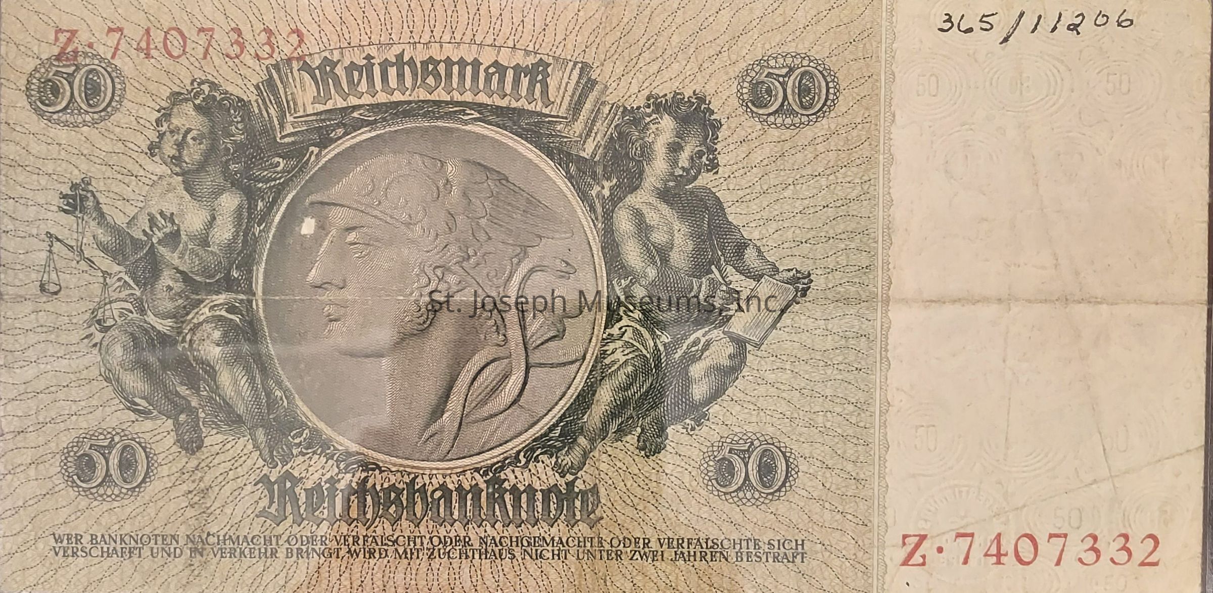 The image displays an old 50 Reichsmark banknote featuring intricate artwork, with a central medallion depicting a helmeted figure in profile, flanked by two cherubs—one holding scales and the other a book. The denomination "50" is prominently shown in the corners, while the serial number is printed in red ink at the top left and bottom right corners. The background consists of wavy lines, creating a textured design. The text "Reichsbanknote" and other inscriptions in German appear below the central artwork, indicating the legal and financial context of the note.