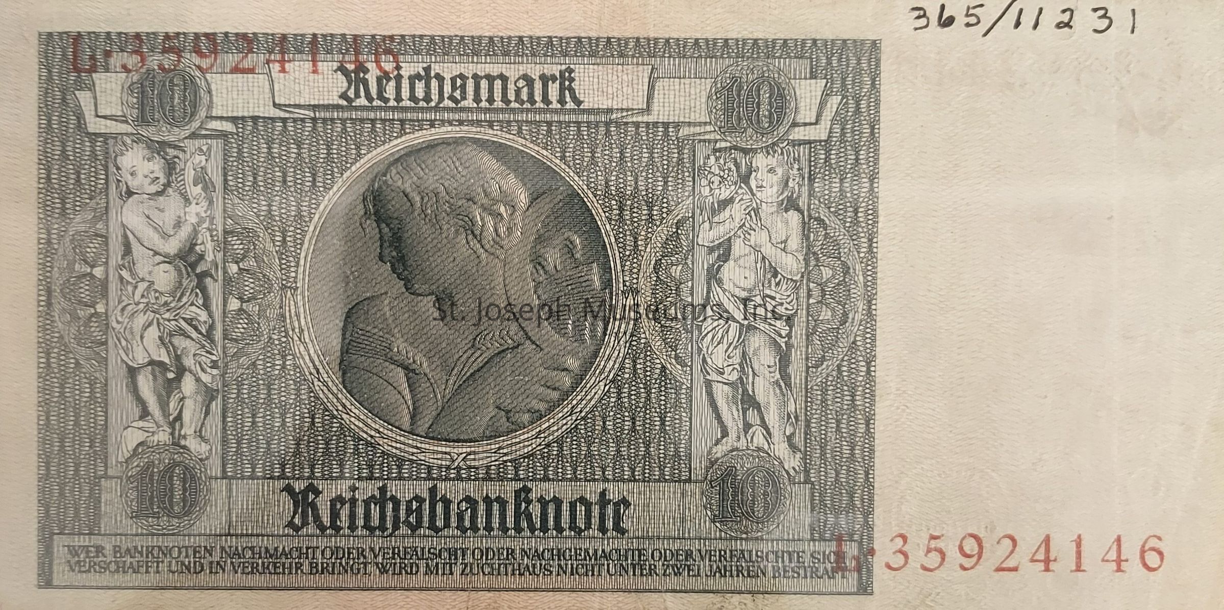 The image displays an old 10 Reichsmark banknote featuring intricate designs and classical art elements, including two cherubic figures on either side of the main emblem with floral motifs, framing a central portrait in profile likely representing allegorical or historical significance, labeled with "Reichsbanknote" at the bottom; the note exhibits detailed engraving work typical of its era, and is marked with red serial numbers on the top left and bottom right, as well as handwritten numbers in the top right, which contribute to the overall historical and monetary context of the note, reflecting its usage and preservation over time.