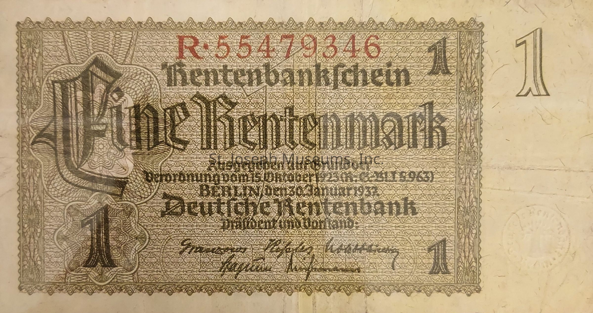 The image shows a historical German banknote, specifically a one Rentenmark note. It features ornate patterns with intricate designs surrounding the text. Prominently displayed in Gothic script is "Eine Rentenmark." The number "1" appears in bold on each corner, emphasizing the denomination. There are several lines of smaller text in German, likely detailing the issuing authority and terms, and a series of signatures at the bottom. A red serial number, "R-55479346," is visible at the top, adding to the note’s distinctiveness and authenticity. The background is textured, with various lines and decorative elements that enhance the classic aesthetic of the period when it was printed.