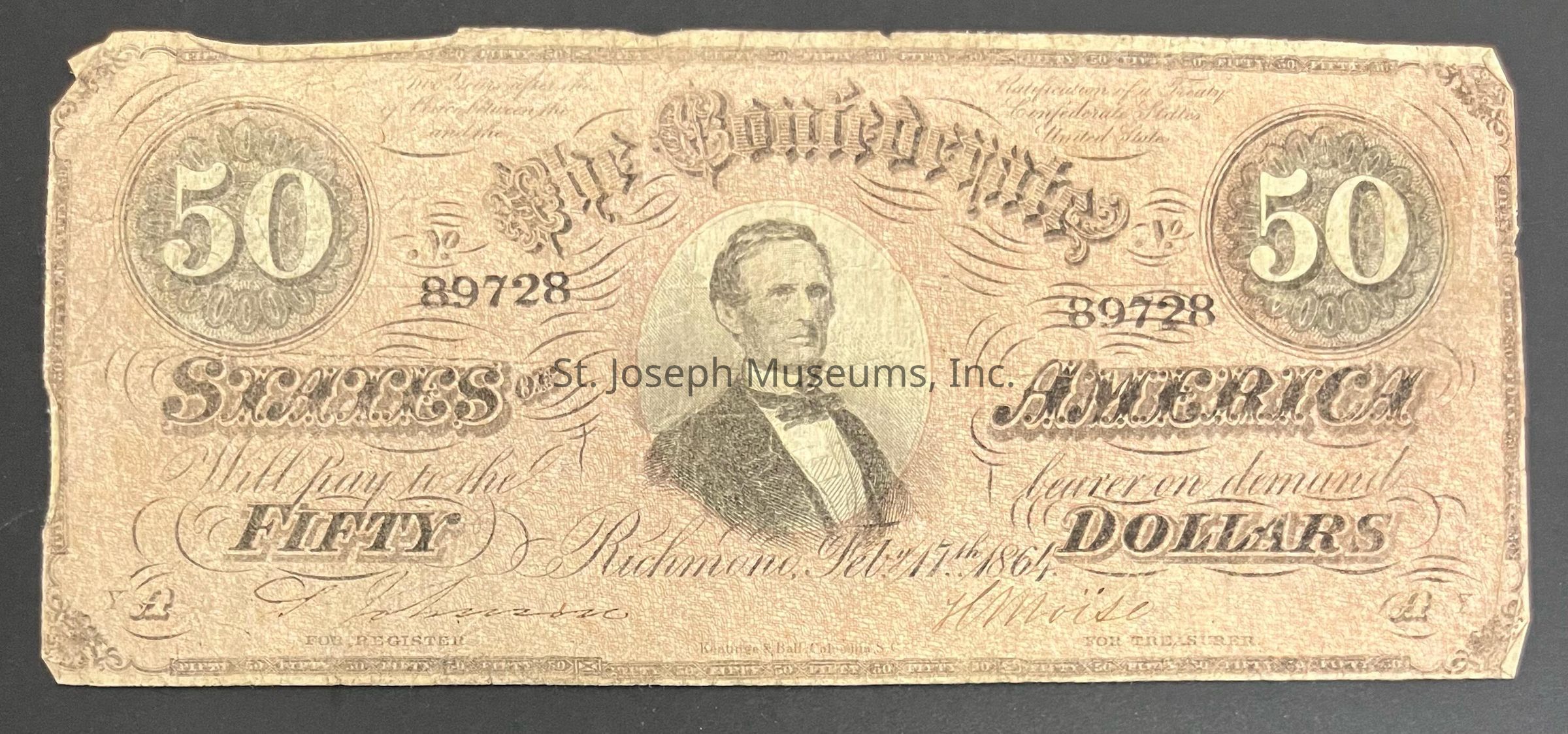The image depicts an old Confederate $50 banknote from the Civil War era, dated February 17, 1864. Its design features intricate patterns and elaborate typography typical of the period. There are large "50" numerals on both the top left and right corners, surrounded by ornate circular designs. In the center, there's an engraved portrait of a man in formal 19th-century attire, adding a historical context. The words "The Confederate States of America" can be seen, indicating its origin. The note is aged, with visible signs of wear, conveying a sense of historical significance and value.