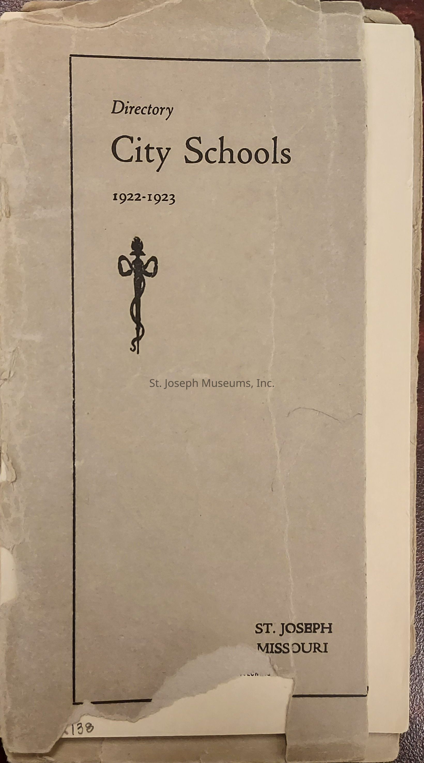 The image depicts a worn-out cover of a booklet titled "Directory City Schools 1922-1923." The cover, showing signs of aging with frayed edges, suggests it's quite old and fragile. A simple decorative emblem is printed below the title, adding a classic touch to the design. The words "ST. JOSEPH MISSOURI" are inscribed at the bottom right, indicating the geographical relevance of the directory. The overall texture and discoloration of the cover reflect its historical significance, possibly serving as an archival document for schools from that era, providing insights into the educational landscape of St. Joseph, Missouri, during the early 20th century.