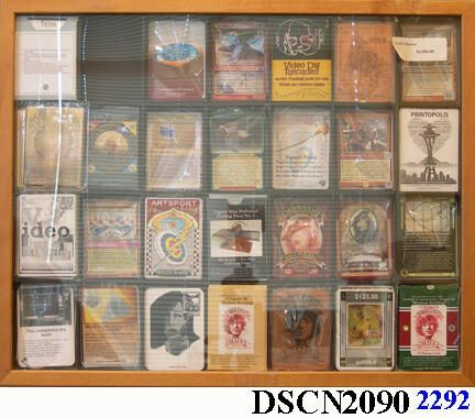 Cased Artistrading Cards Archive Cased: Twenty-eight compartments for decks of artistrading cards framed under acrylic with a hinged system to allow opening the case to examine each deck. The cards are prototypes for vaguely described games, some that are described in a book titled, "Artist's Collectible Trading Cards and Games." In part I of this book I catalogued the artist’s trading cards I made from the late 1990s to 2015. The cards took a variety of forms, styles, and materials - one set is made of etched copper plates intended to be printed on an etching press. In Part II, I offered ten easy games copied from the Dummies Series, modified to help a novice like me get into the swing of card games that underlie many TCGs. I am neither a player nor collector myself, therefore from "Collectible Trading Card Games for Dummies," I copied over ten simple games. In this way I hoped to invent one of my own. By learning the game mechanics of simple games - which are on the market already - I thought I could arrive at an original artist’s collectible trading card game. Playing the role of a failed art professor (despite that my nineteen years’ teaching at the University of Washington I may appear to be anything but a failure) I had risked all to teach - and lost. Be that as it may, my game-of-life is not over and I believe I will achieve something great in my teaching, because - to my mind - teaching is of greater importance to humanity than art or games alone. The three, however, are complementary – effective teaching may be in an interactive triad, but without the discipline of teachers,’ artists’ and gamers’ contributions, their importance is at risk. As an educated population is the secret of successful democracy, and as mechanization has taken command of so much of civilization, it may be that playing games is a better way to learn and teach than has been understood. Artist’s collectible trading card games is my way of exploring, and my book and this collection documents my process. In March, 2023, this was used in building the Escape Emeralda game. It refers to fractionalized ownership of artiscrip or artiscryp, and the possibility of buying only a few dollars' worth of the item as a share in the Printmaking Toys and Games Factory. However, until this version can be in effect, the piece can only be owned in artiscrip as 100% share. The owner has the right to fractionalize it by his or her own method, returning 10% of gross net to the author, me, Bill H. Ritchie.