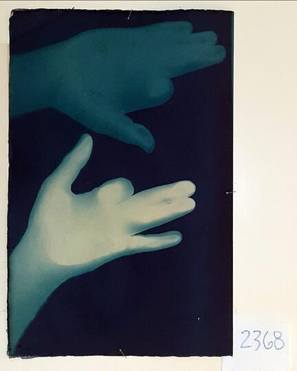 Handmade Dog Cyanotype No. 30 of 32: Norman Durkee, a Seattle composer, was a friend of mine and he sent me a tape of works made on his new Buchla synthesizer. One was titled, "Handmade Dog," a silly, rambling ditty with his synthesized "Woof woof" interspersed. My thought was to collaborate with Norman with my own handmade dogs. I had been doing such hand-shadow prints for some time. The technique, cyanotype, is sometimes called "sun printmaking" because sunlight is ideal, especially in months when the sun is high and rich in UV. The method requires coating paper with chemicals, letting it dry in a dark place, and then - in the sun as I did in this series - laying the paper out flat and putting like one's hand on it. Where the sun strikes the chemical, a reaction occurs and after some seconds or a minute, the paper is shielded until it can be washed. In cold, running water, the unexposed chemicals dissolve and wash away. Where the sun struck, the chemicals became insoluble and turn blue. Invented at the time many photo processes were (the mid-19th Century), it never achieved commercial value except in making blueprints and fine art photographs. To make the series of 32 prints I made a cyanotype or two a day in the summer of 1982, climbing to the rooftop hatch to the top of the Journal of Commerce Building in Seattle, which was home to the Triangle Studios for me from 1977-1983. See my memoir, "Dumb Hope: My curious life - 1981-1990."