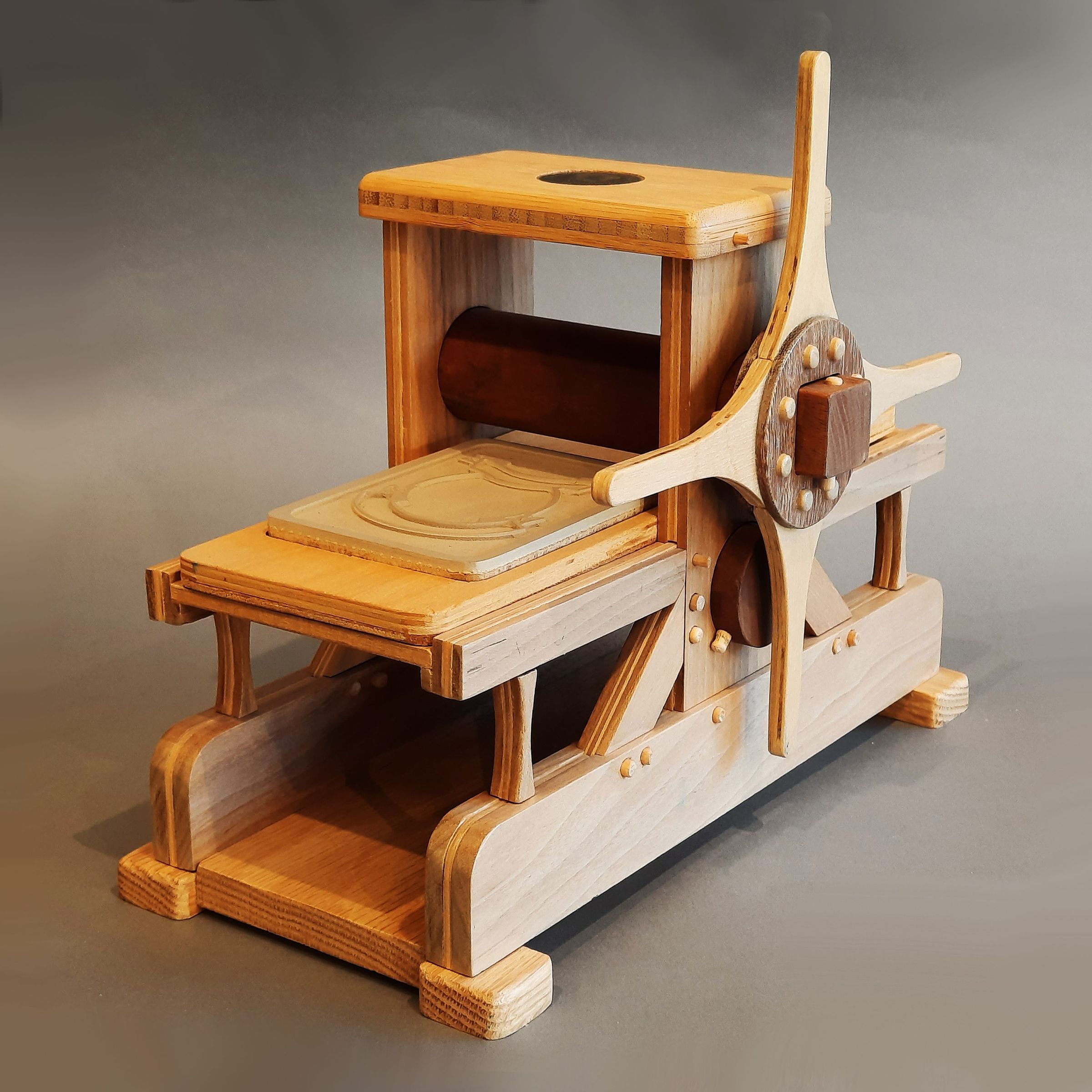 WeeWoodie Rembrandt Press - Stretch version: This unique printing press from the Bill Ritchie Halfwood press line is a 1/6 scale model inspired by Rembrandt's etching press replica in the Rembrandthuis museum. Known as the WeeWoodie Rembrandt Press, it is a collectible, functional miniature crafted from walnut, bamboo, purple heart, and fine veneers, intricately assembled with wooden pegs. Designed by Bill Ritchie and expertly crafted by Ric Miller using his CNC router, this conversation piece comes with two printing plates and a test print made in 2014. Whether you're a printmaking aficionado or a lover of finely crafted miniatures, the WeeWoodie Rembrandt Press is a valuable addition and provides considerable pride of ownership. Similar ones have been marketed worldwide, but only one other like it exists in a private collection. Numerous videos can be found on YouTube on Bill's channel. An 8-minute video of this one may be seen on YouTube (copy and paste this in your browser-https://youtu.be/lPmEmYmJMlM ). Mr. Ritchie created a deep, online presence so collectors may dig into their treasure's backstory at emeraldaworks.com.