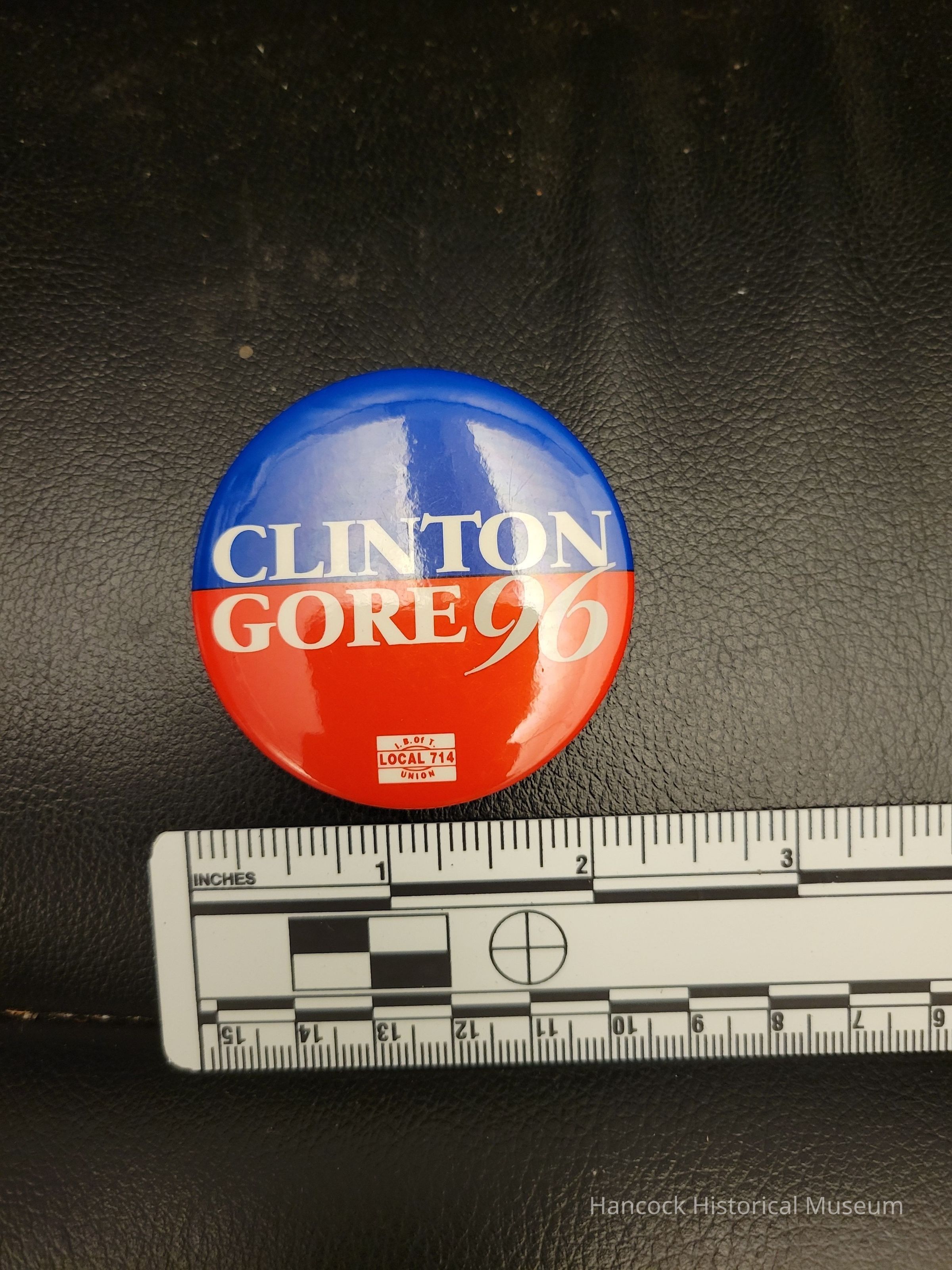 The image features a round button with a prominent graphic design comprising a blue upper half and a red lower half, displaying the text "CLINTON GORE 96" in bold white letters, signifying the 1996 political campaign. Below this text, a small emblem reads "I.B. of T LOCAL 714 UNION," indicating a connection to a labor union.