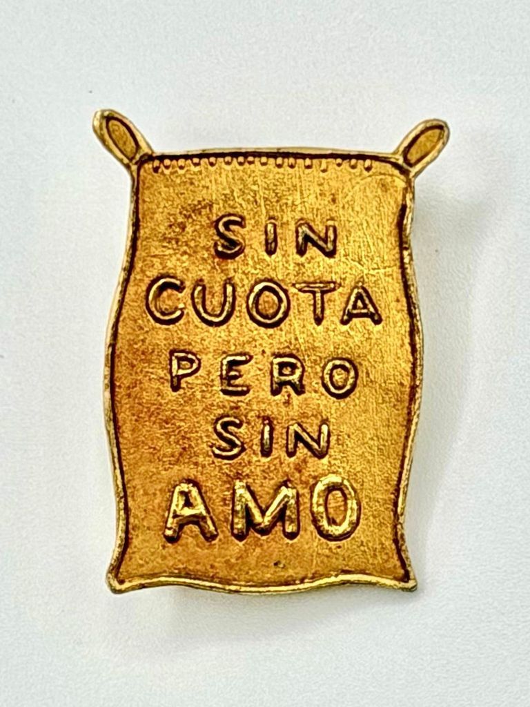 Political-slogan lapel pin — "Sin cuota pero sin amo" (sugar-sack form)