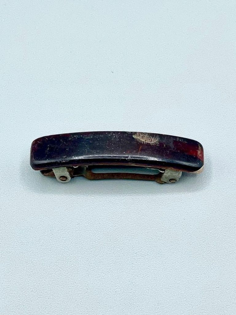 Hair barrette with dark plastic cover and metal spring clasp