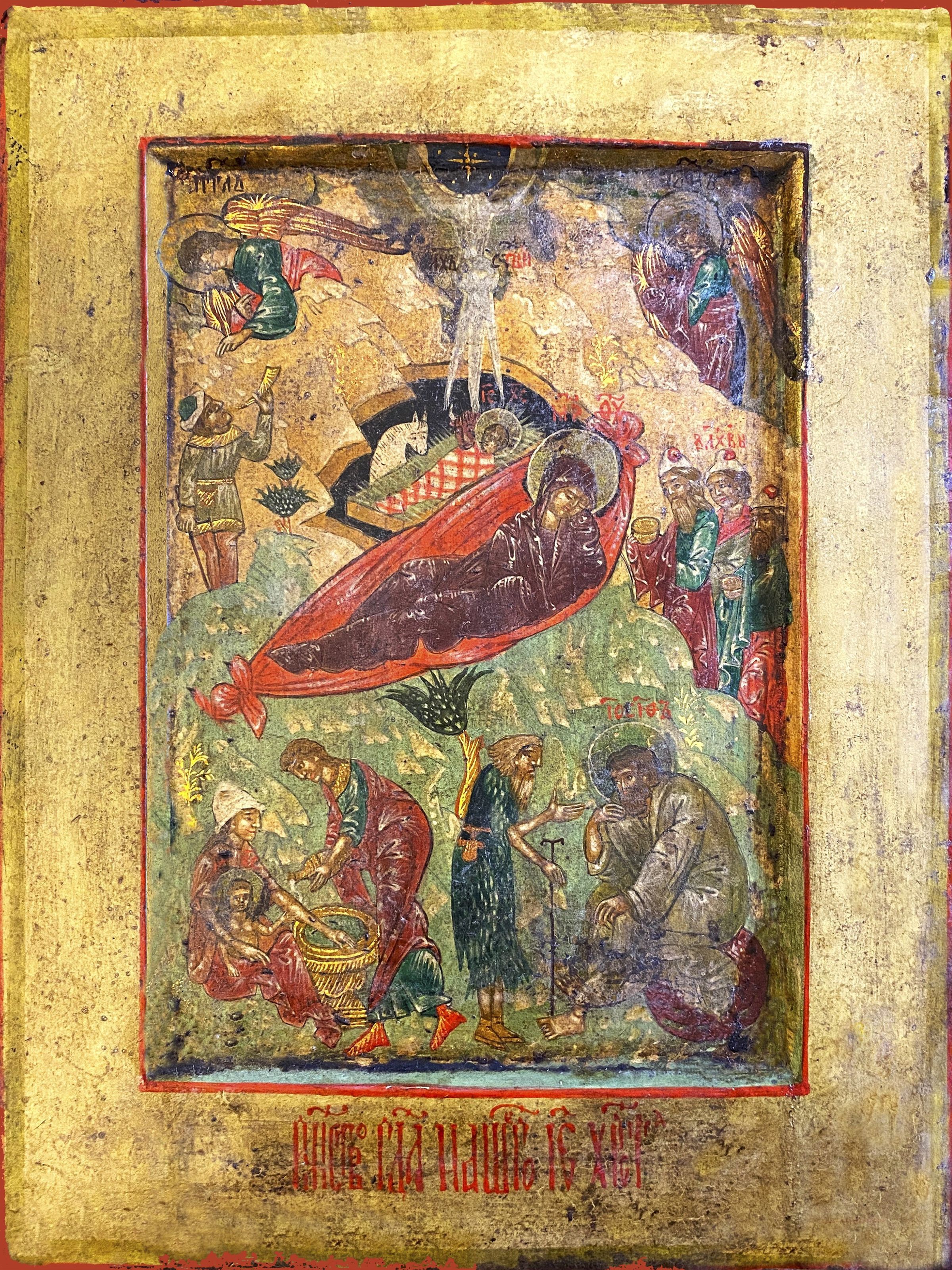 This icon showcases a Nativity scene. In the center, Mary reclines on a vibrant red bed. An angel at top left delivers a message to a shepherd, while Wise men enter from center right. Below, a midwife washes a baby while two old men discuss these events. Natural and celestial elements provide the backdrop; a golden frame enhances the sacred atmosphere. Cyrillic text says The Nativity of Our Lord Jesus Christ.