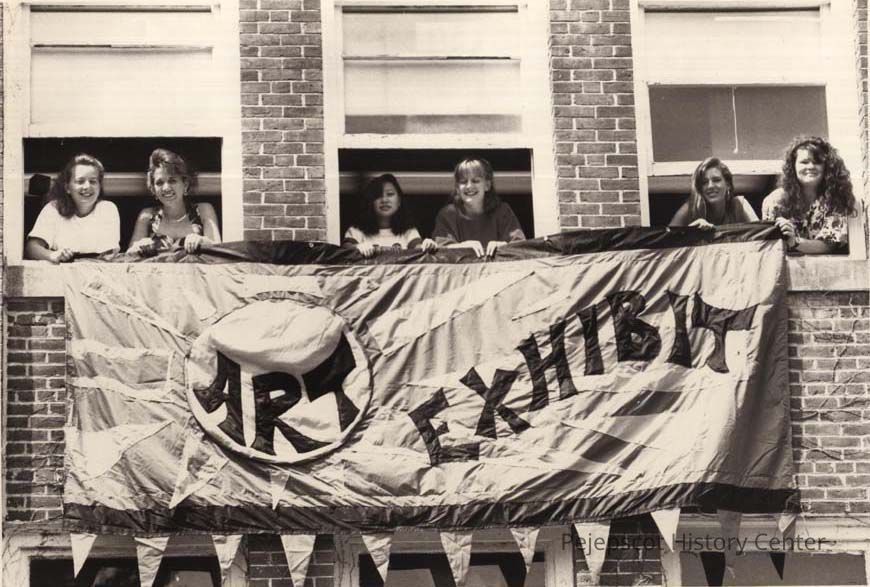 Brunswick High School Art Exhibit banner: A black and white photograph of students advertising the Brunswick High School Art Show, Brunswick, Maine. Six students are holding a crafted banner announcing the art exhibit from the second floor of the High School.
This photo was published in the Times Record newspaper on 06/08/1992.