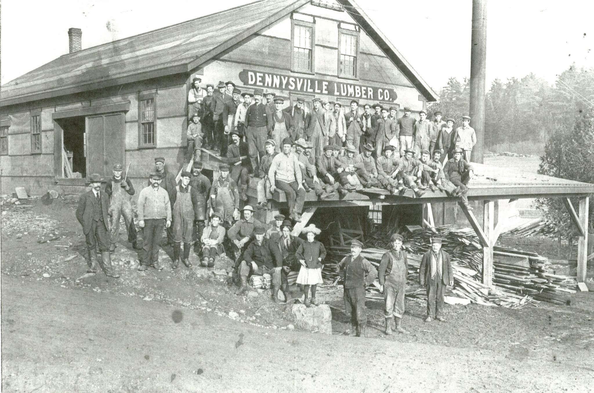 Dennysville Lumber Company, 1907; Dennysville Lumber Company workers pose for a picture beside their new mill building, with young Marie Mahar who happened along just in time.